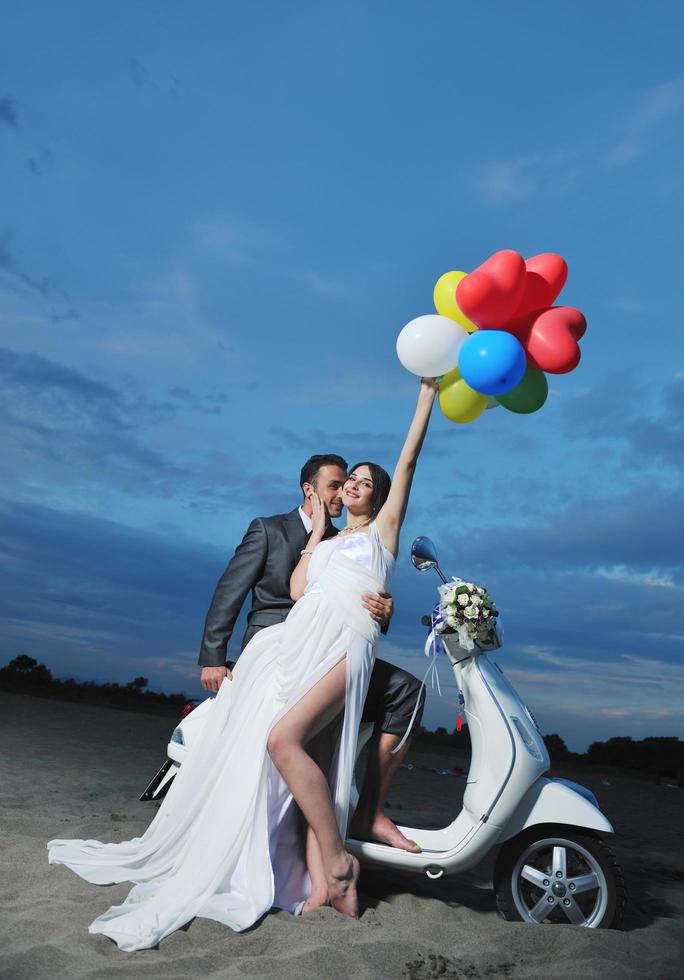 just married couple on the beach ride white scooter photo
