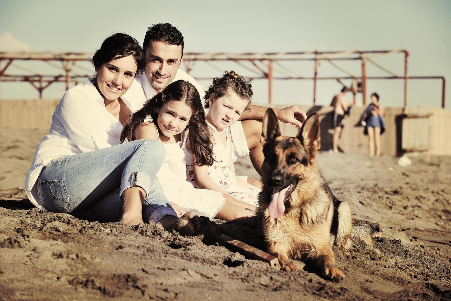 happy family playing with dog on beach photo
