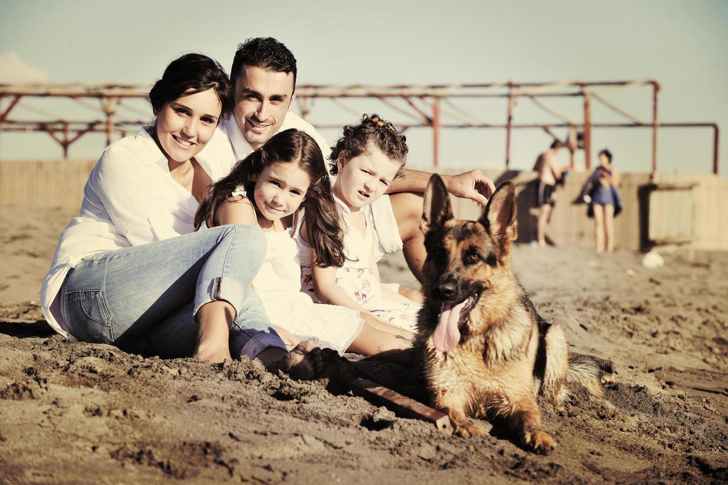 familia feliz jugando con el perro en la playa foto