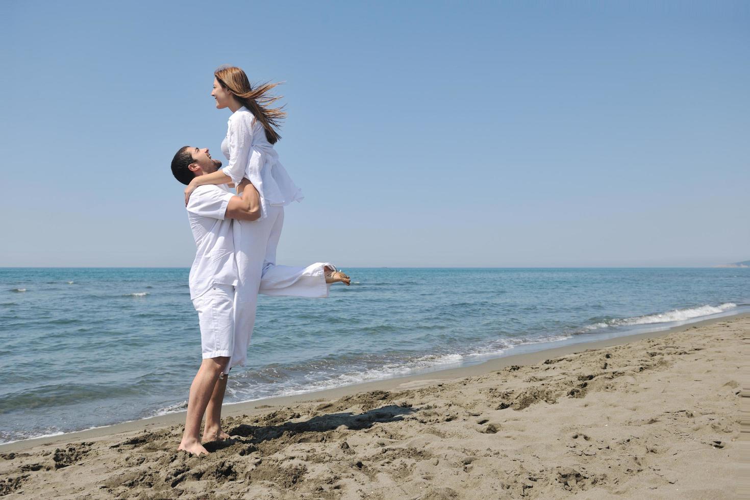 feliz pareja joven divertirse en la playa foto