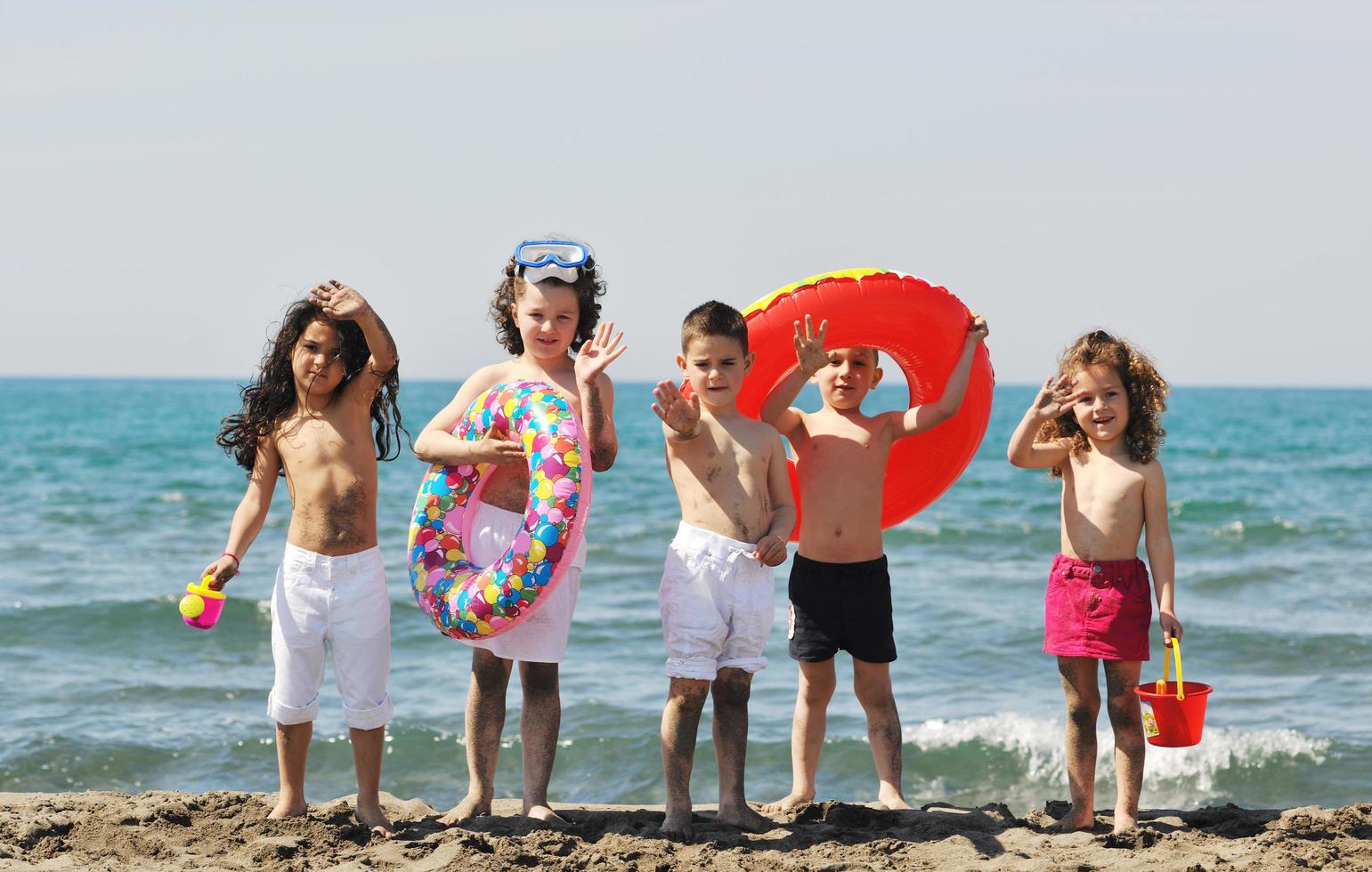 grupo infantil divertirse y jugar con juguetes de playa foto