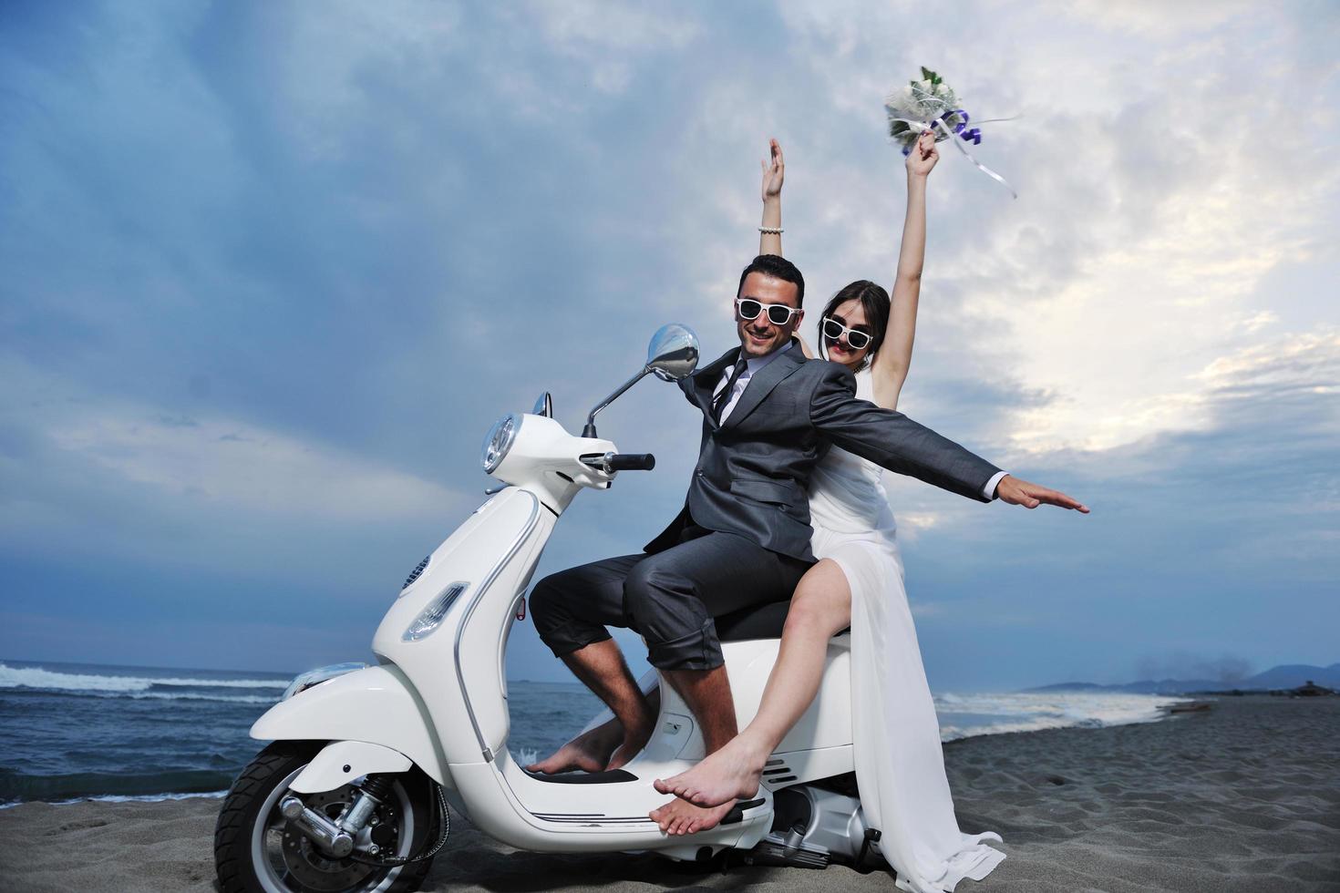 pareja de recién casados en la playa paseo scooter blanco foto