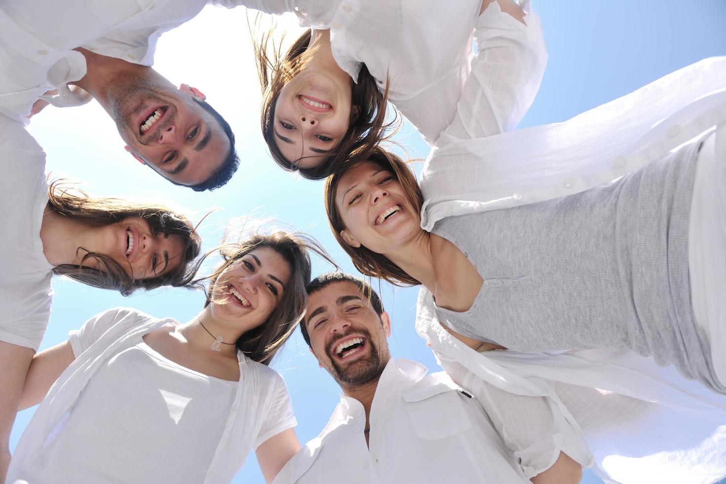 Group of happy young people in circle at beach photo