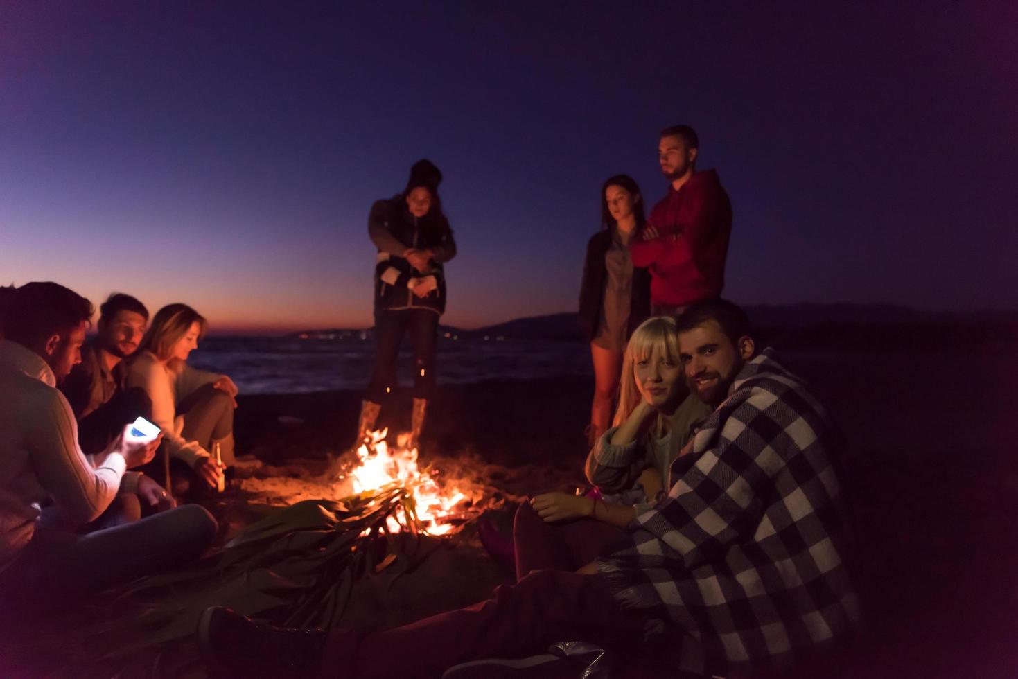 pareja disfrutando con amigos al atardecer en la playa foto