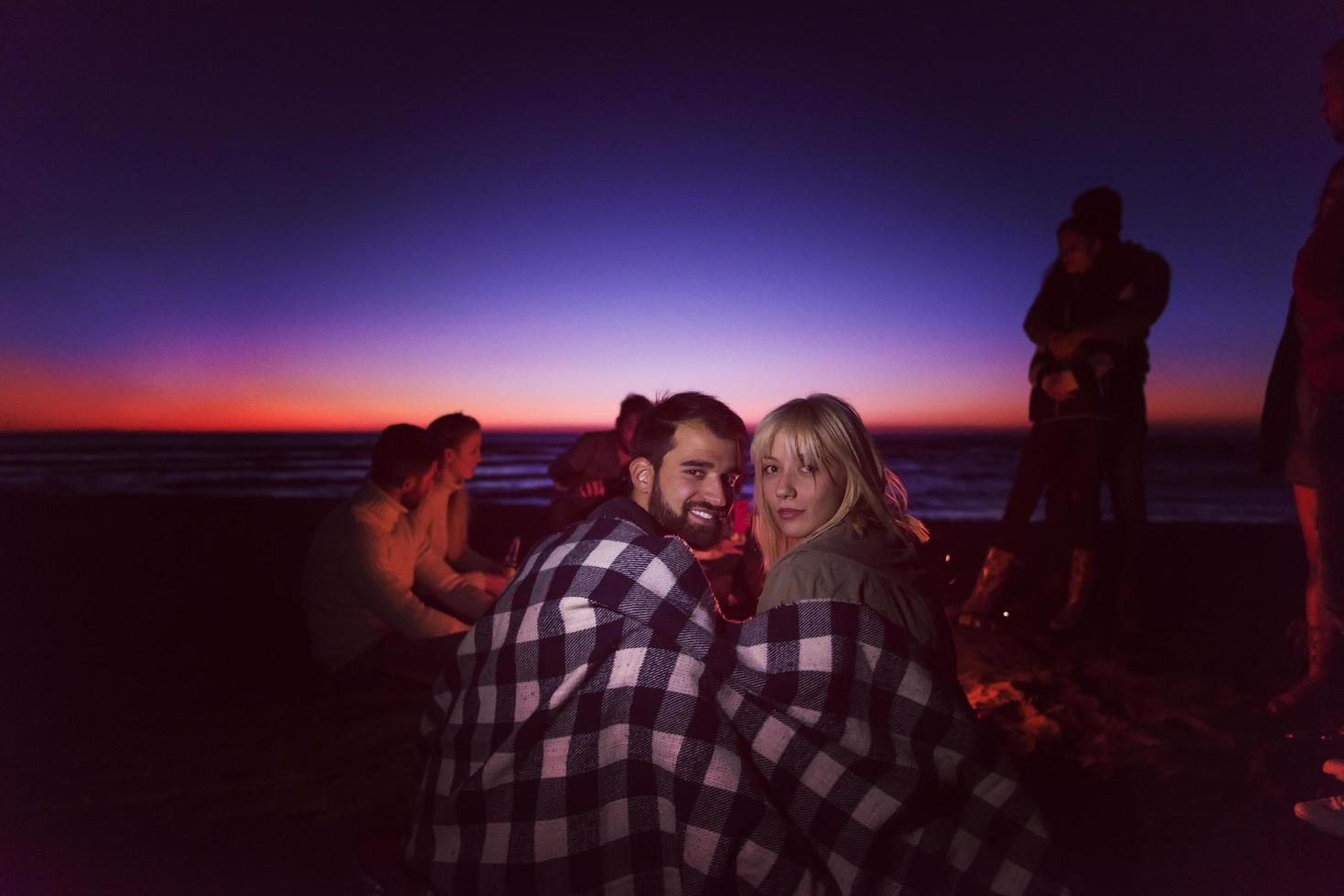 Couple enjoying with friends at sunset on the beach photo