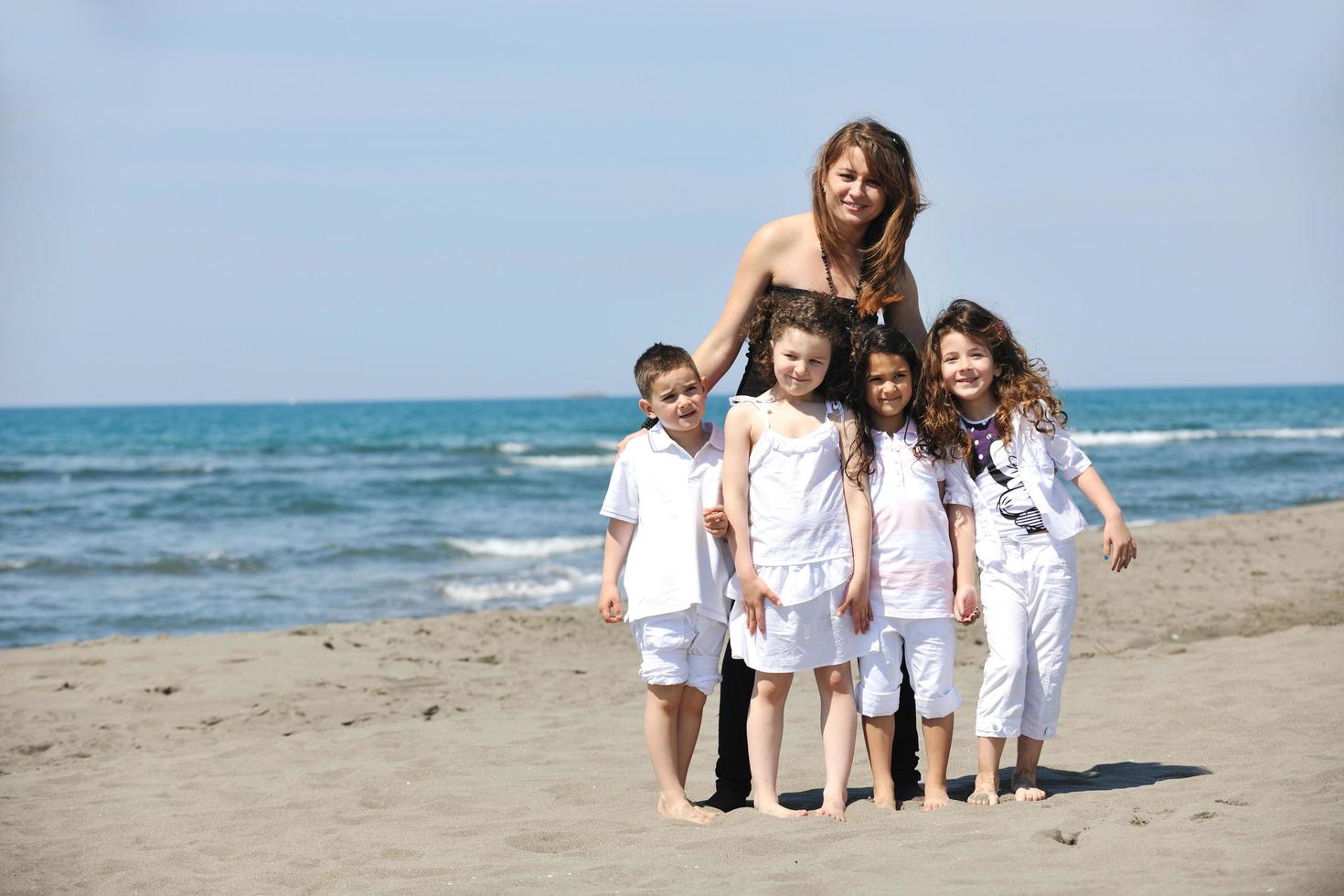 group portrait of childrens with teacher on beach photo