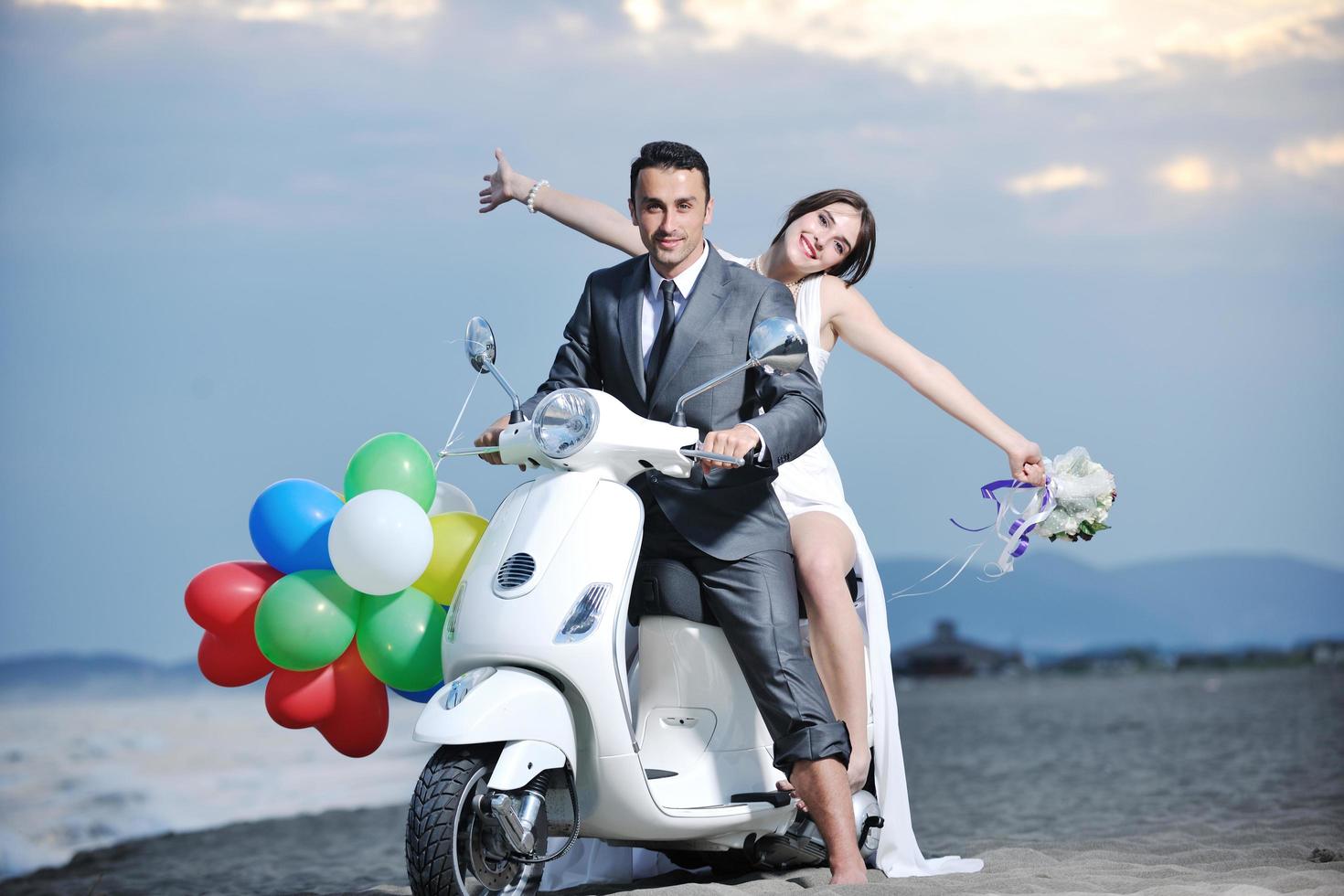 just married couple on the beach ride white scooter photo