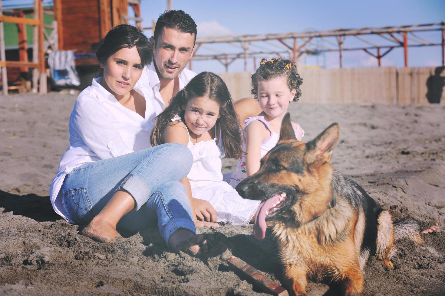 familia feliz jugando con el perro en la playa foto