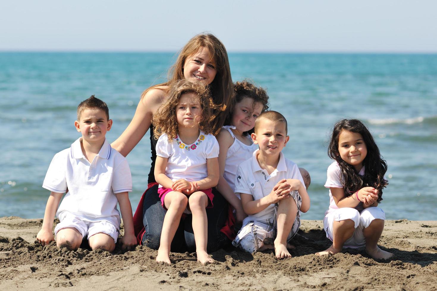 group portrait of childrens with teacher on beach photo