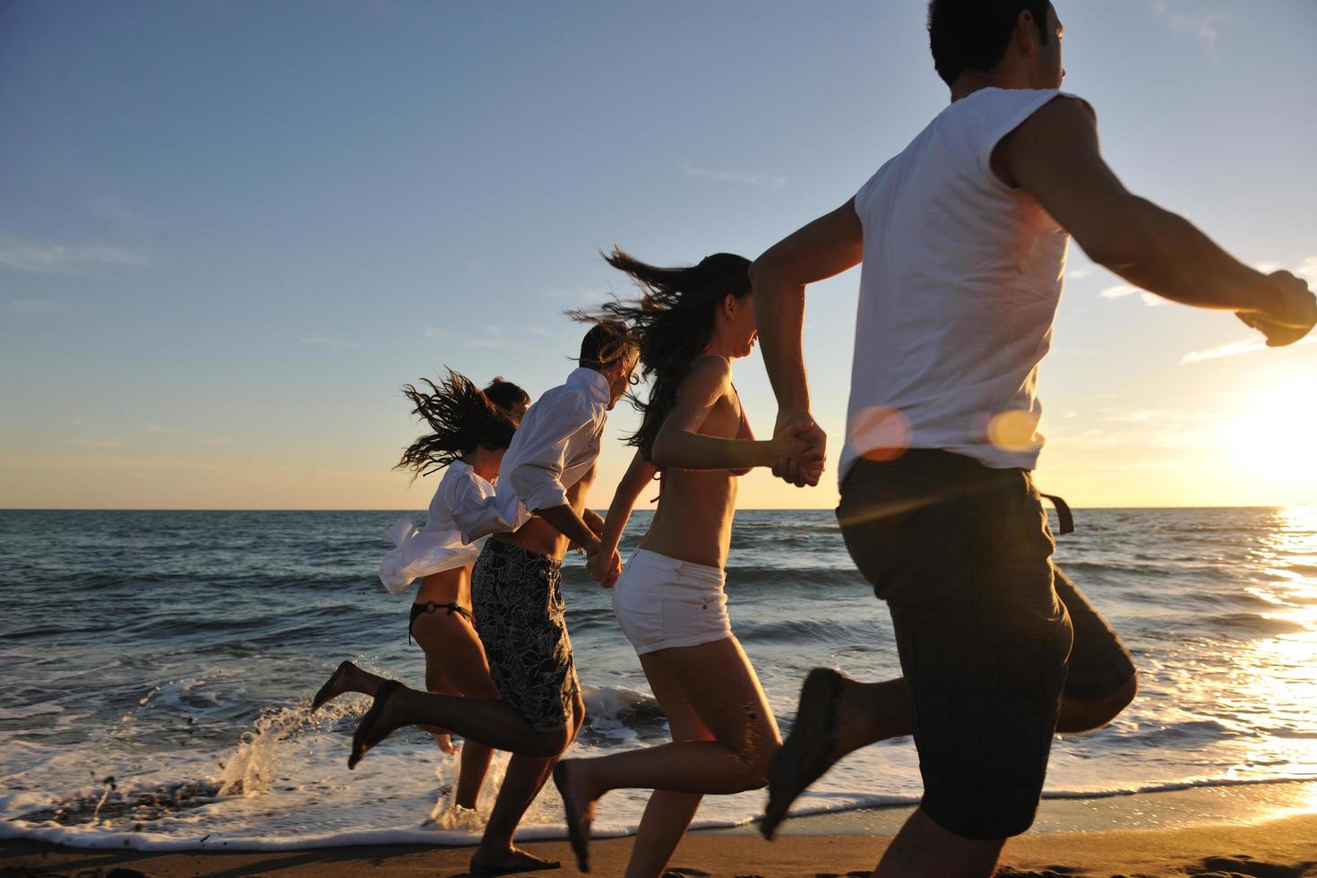 grupo de personas corriendo en la playa foto