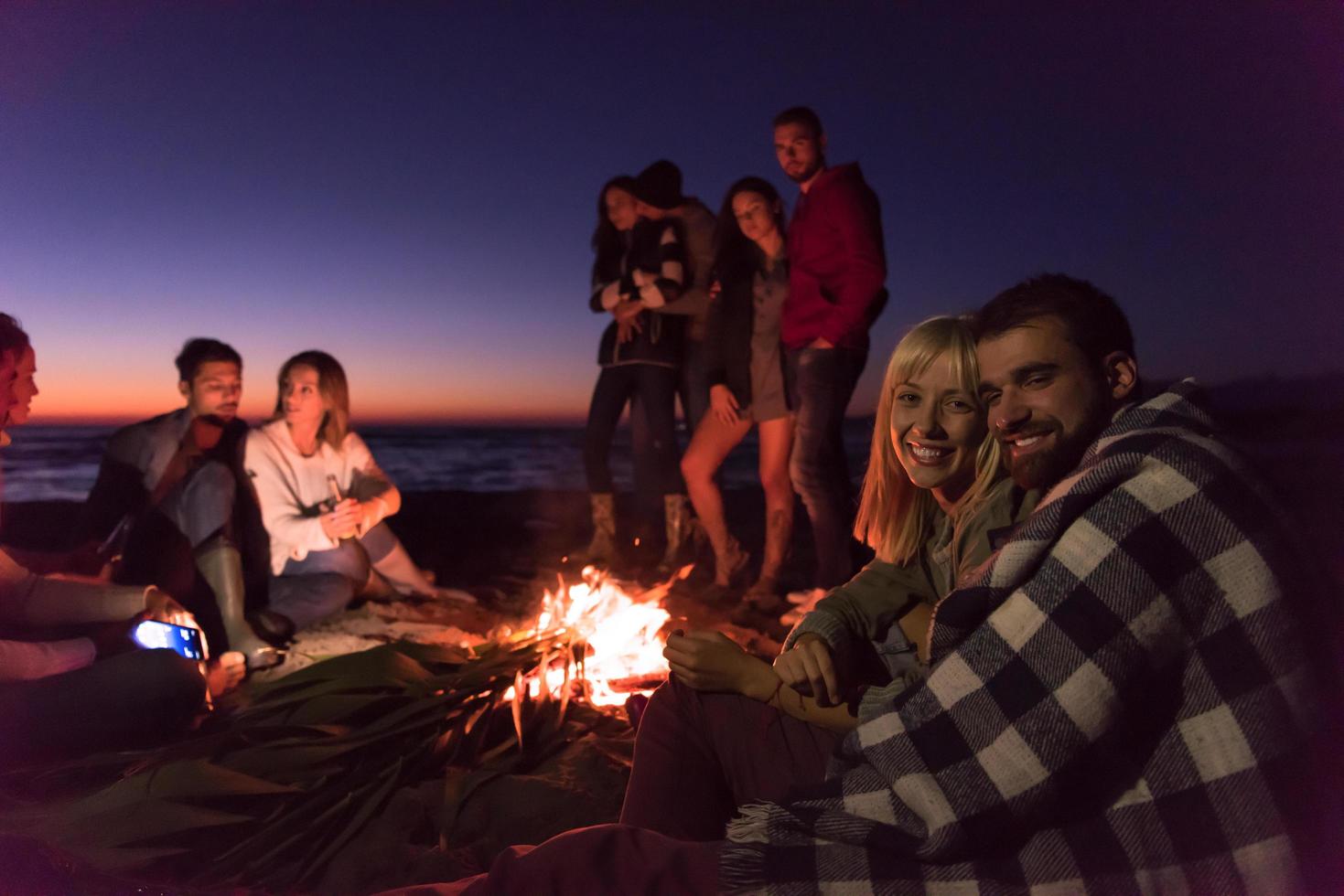 Couple enjoying with friends at sunset on the beach photo