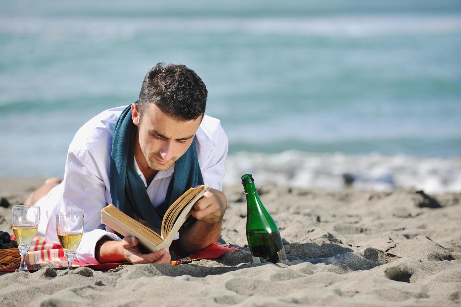 man reading book at beach photo