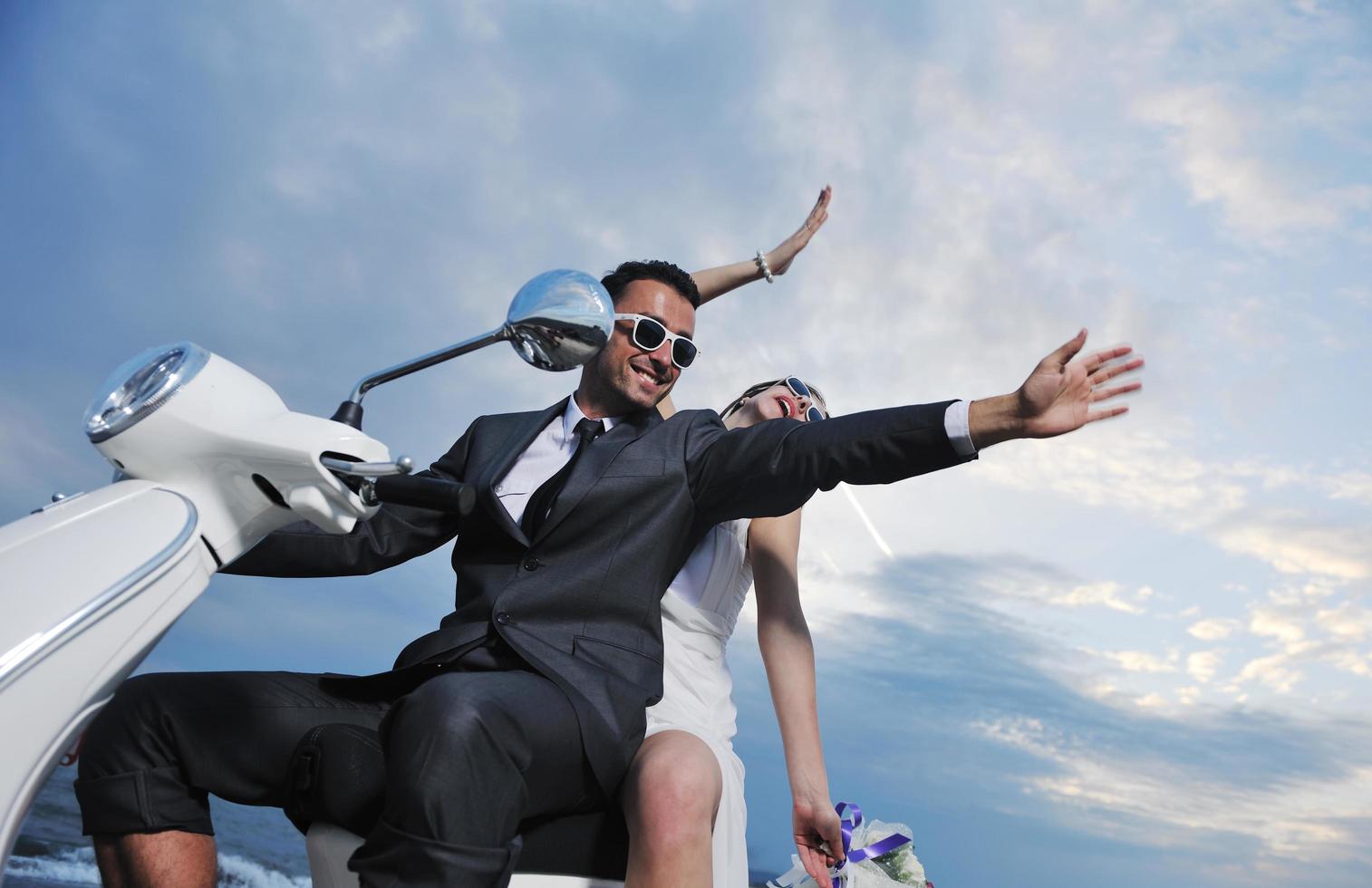 just married couple on the beach ride white scooter photo
