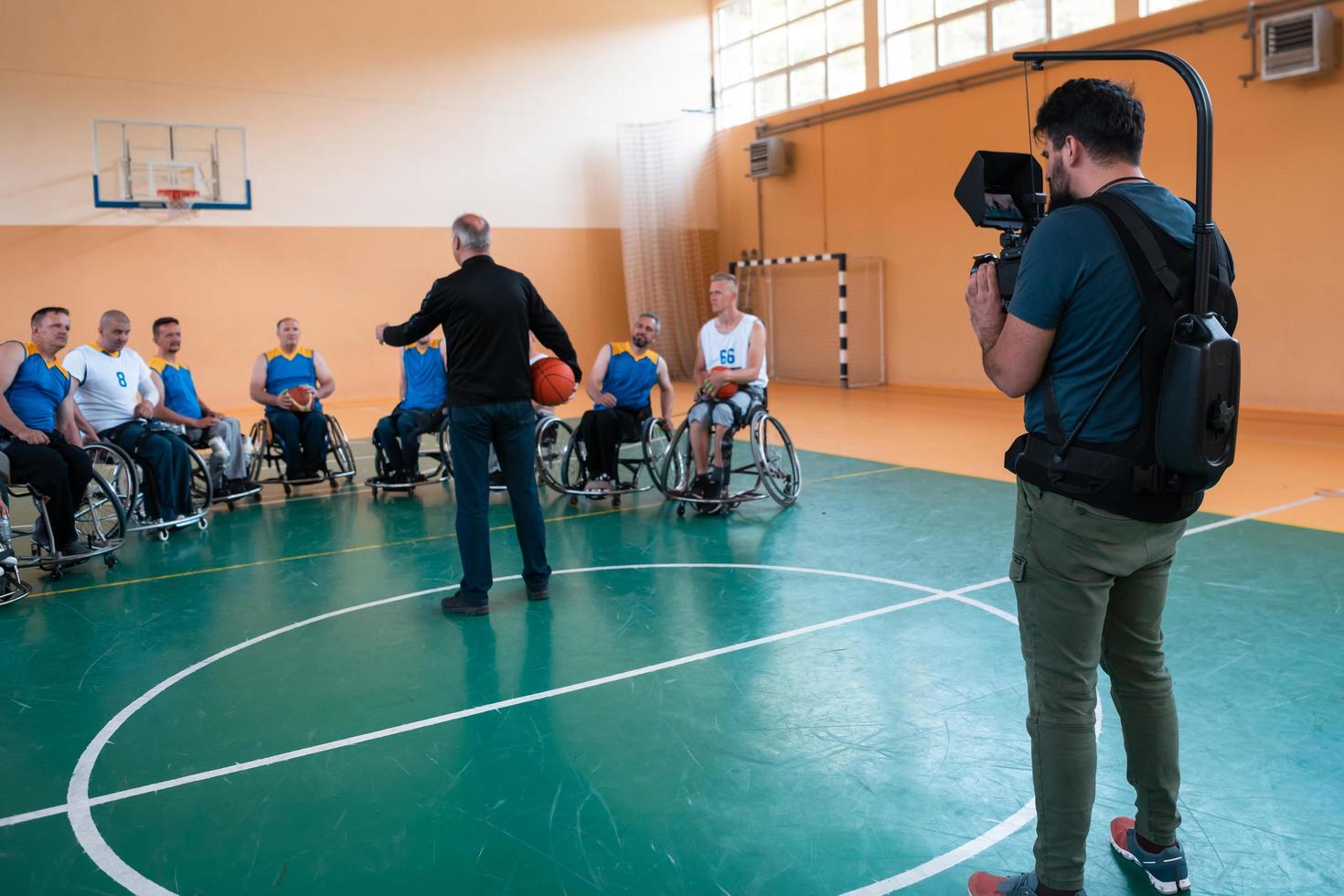 a cameraman with professional equipment records a match of the national team in a wheelchair playing a match in the arena photo
