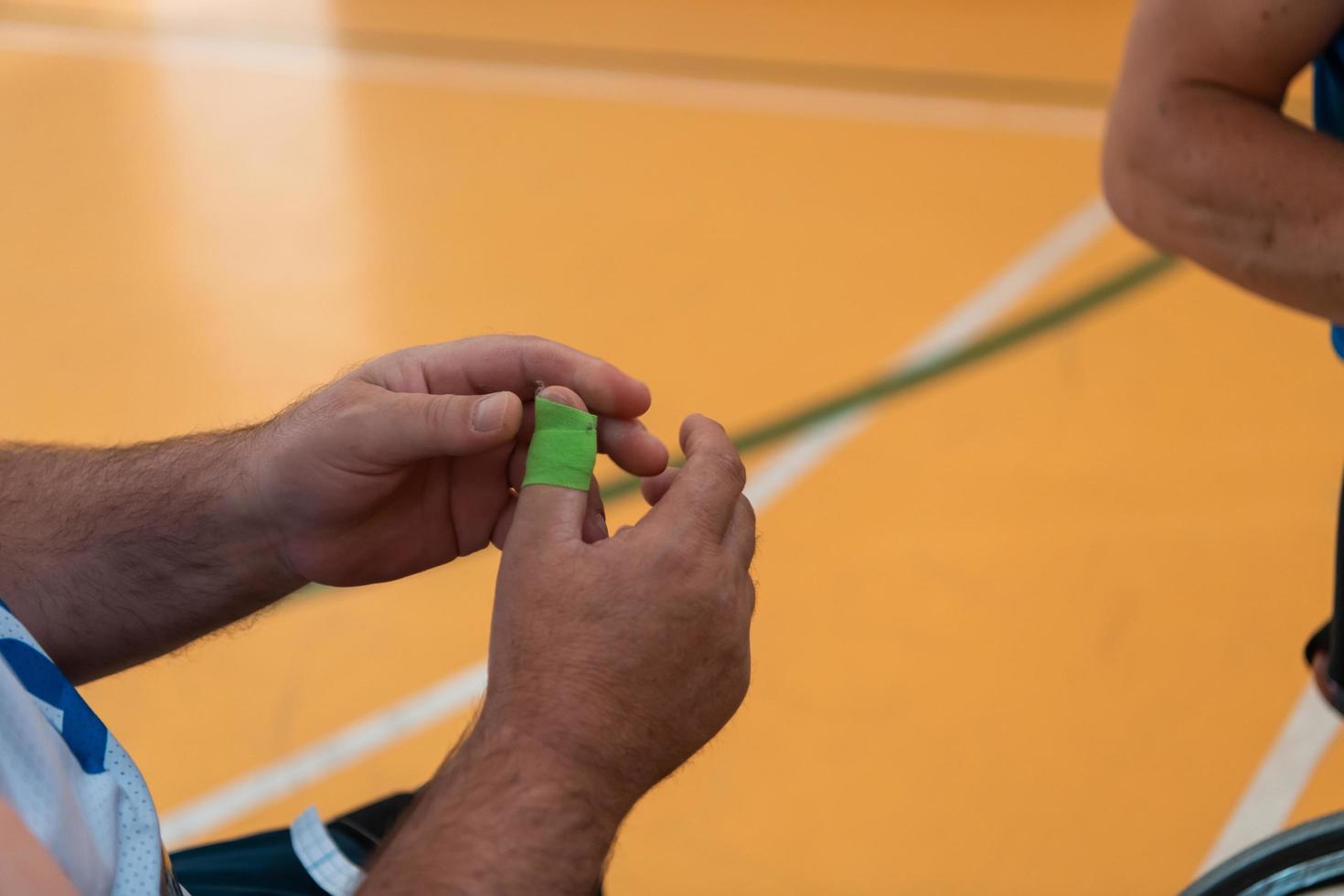 a disabled basketball player puts on a corset and bandages on his arms and fingers in preparation for a game in the arena photo