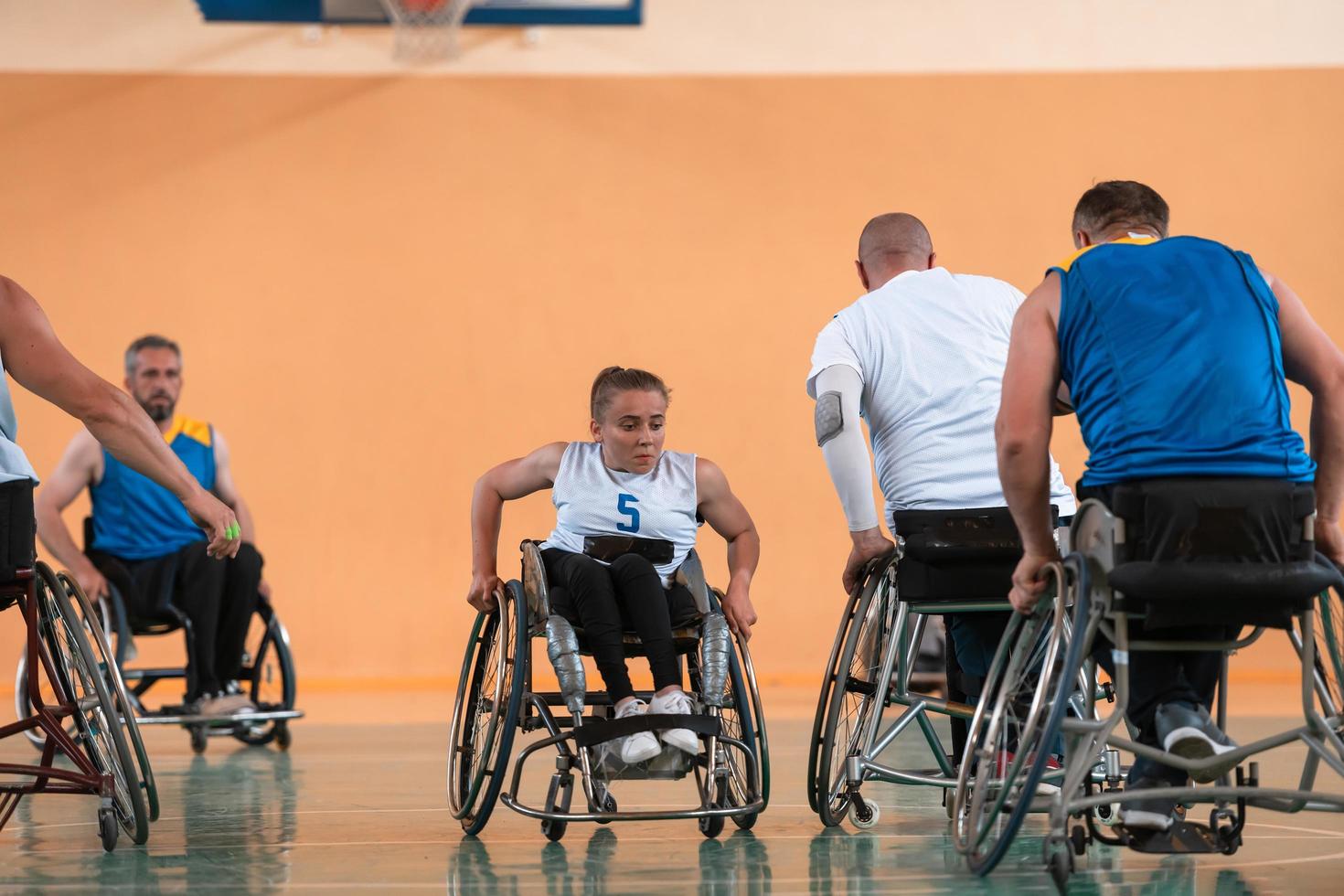 Disabled War veterans mixed race and age basketball teams in wheelchairs playing a training match in a sports gym hall. Handicapped people rehabilitation and inclusion concept photo