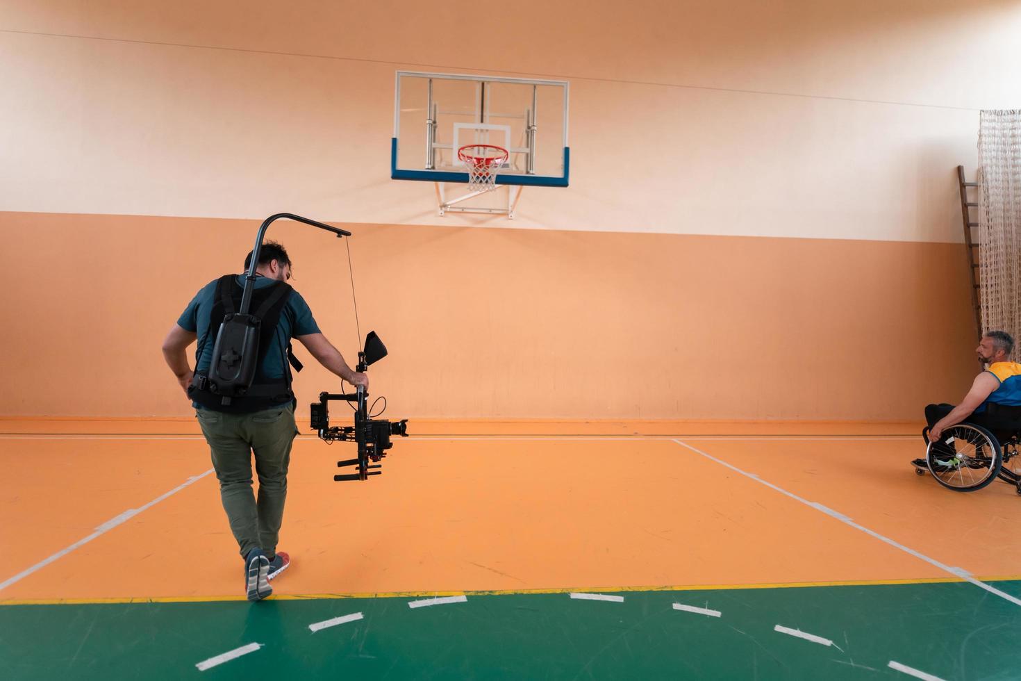 a cameraman with professional equipment records a match of the national team in a wheelchair playing a match in the arena photo
