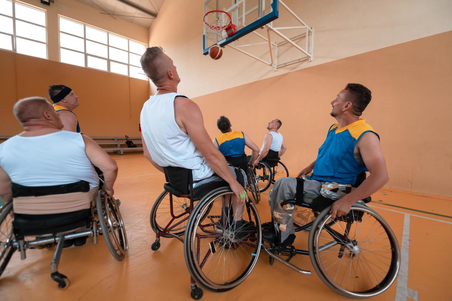 Disabled War veterans mixed race and age basketball teams in wheelchairs playing a training match in a sports gym hall. Handicapped people rehabilitation and inclusion concept photo