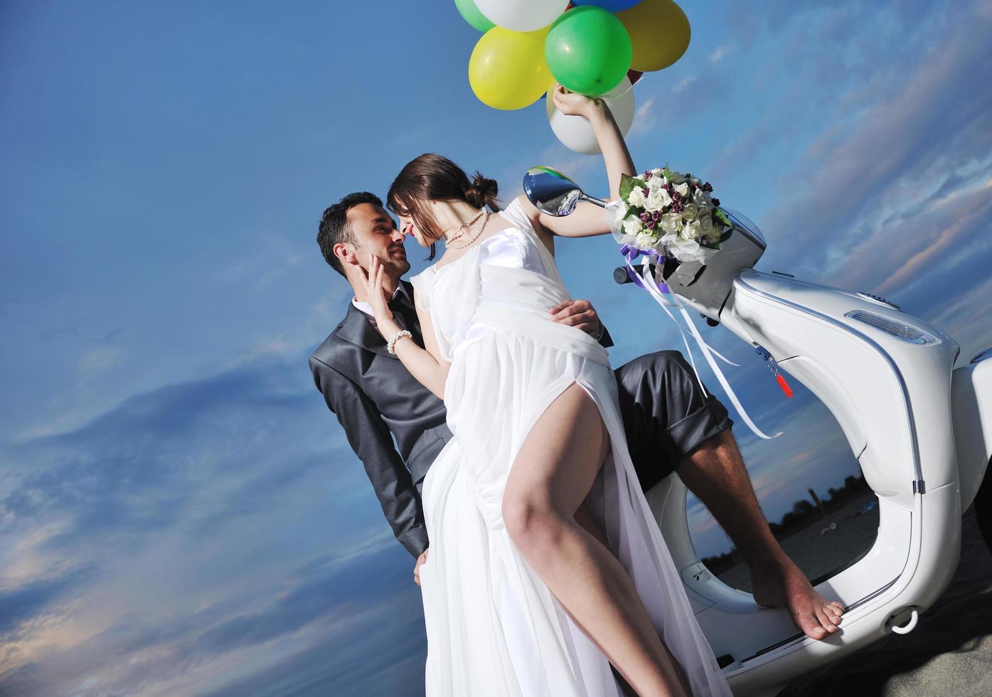 just married couple on the beach ride white scooter photo