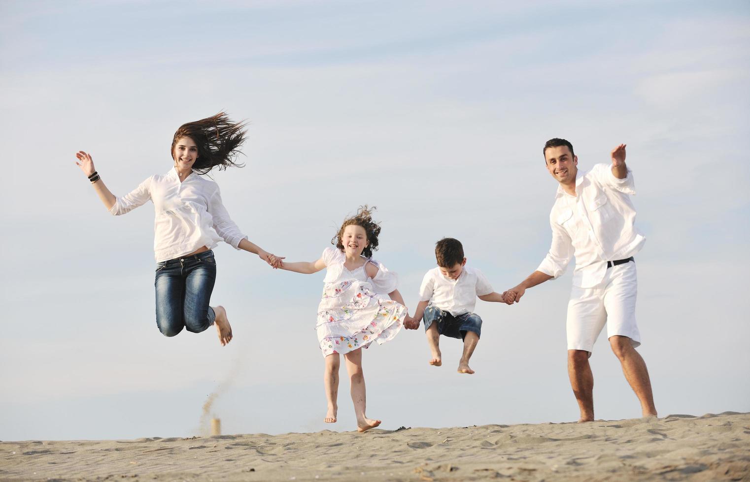 familia joven feliz divertirse en la playa foto