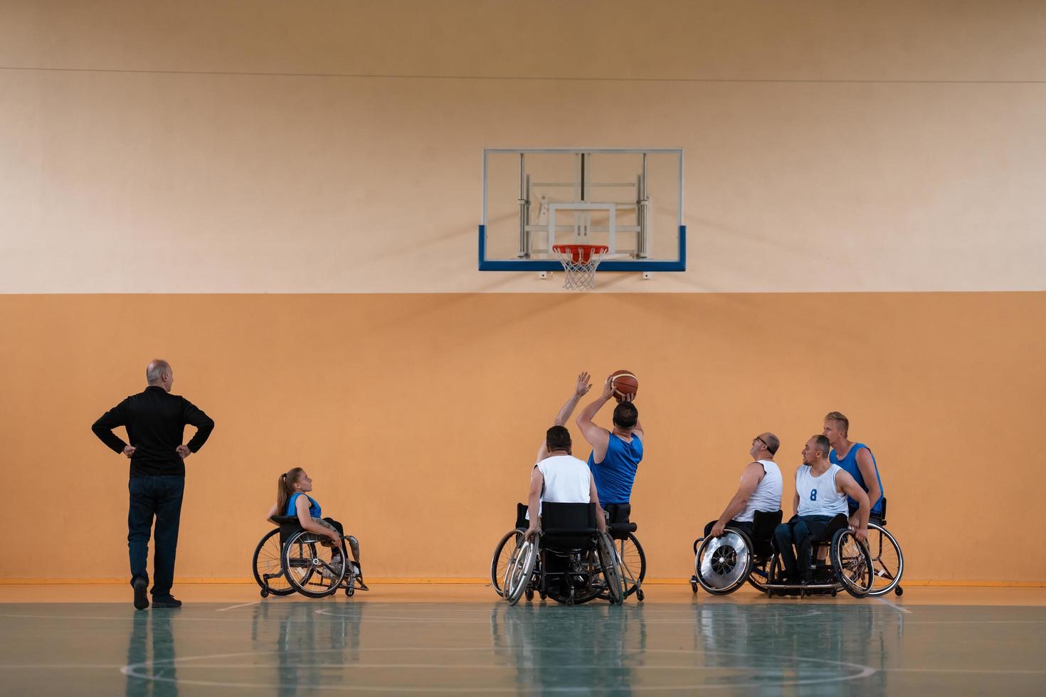 Disabled War veterans mixed race opposing basketball teams in wheelchairs photographed in action while playing an important match in a modern hall. photo