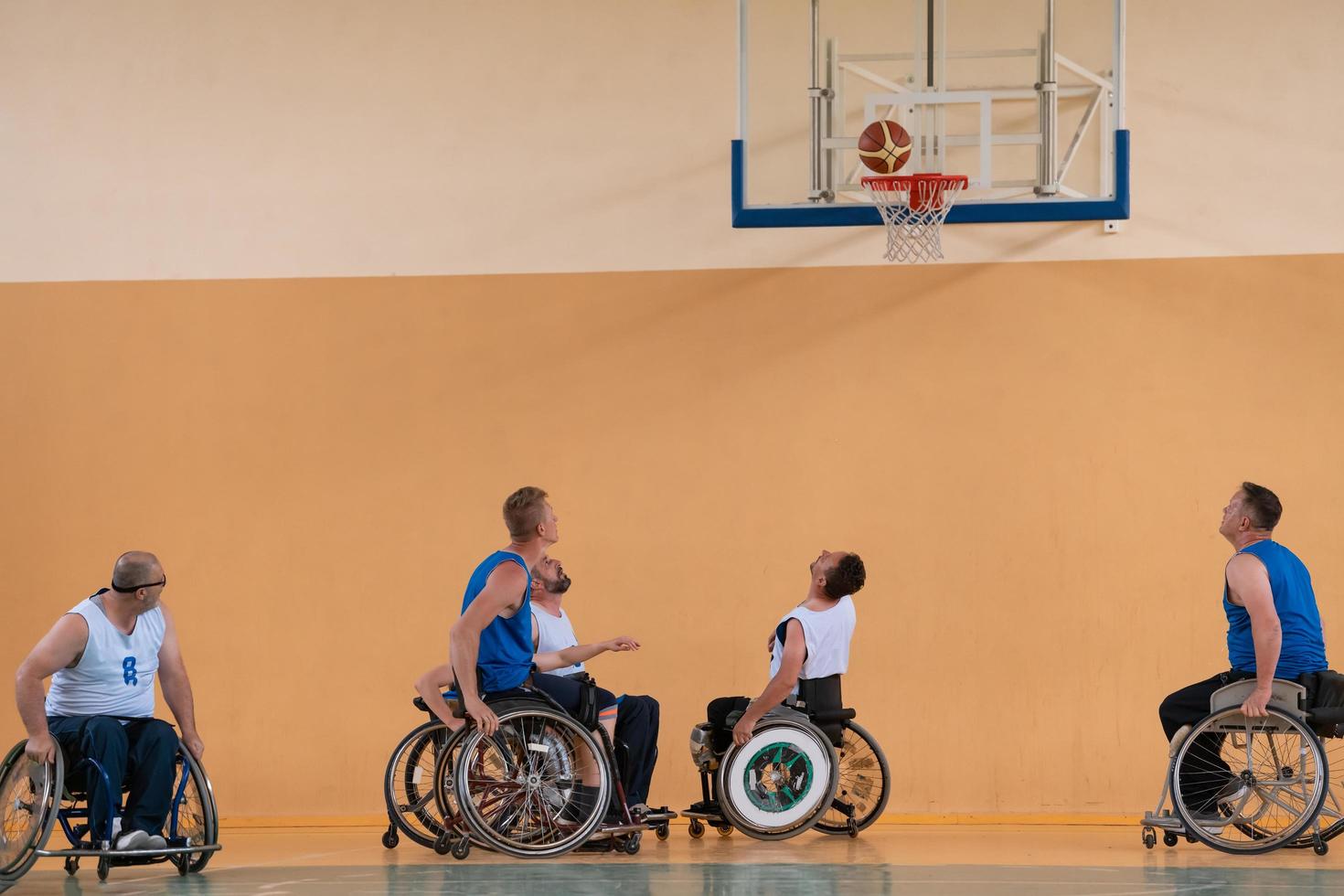 Disabled War veterans mixed race opposing basketball teams in wheelchairs photographed in action while playing an important match in a modern hall. photo