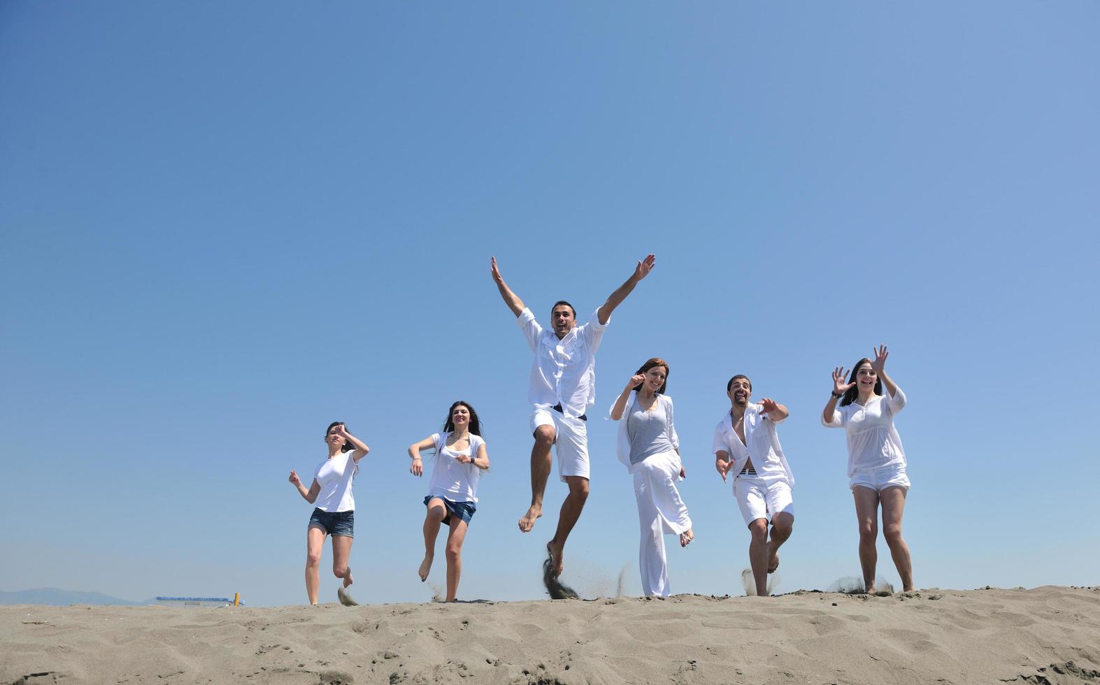 grupo de gente feliz divertirse y correr en la playa foto