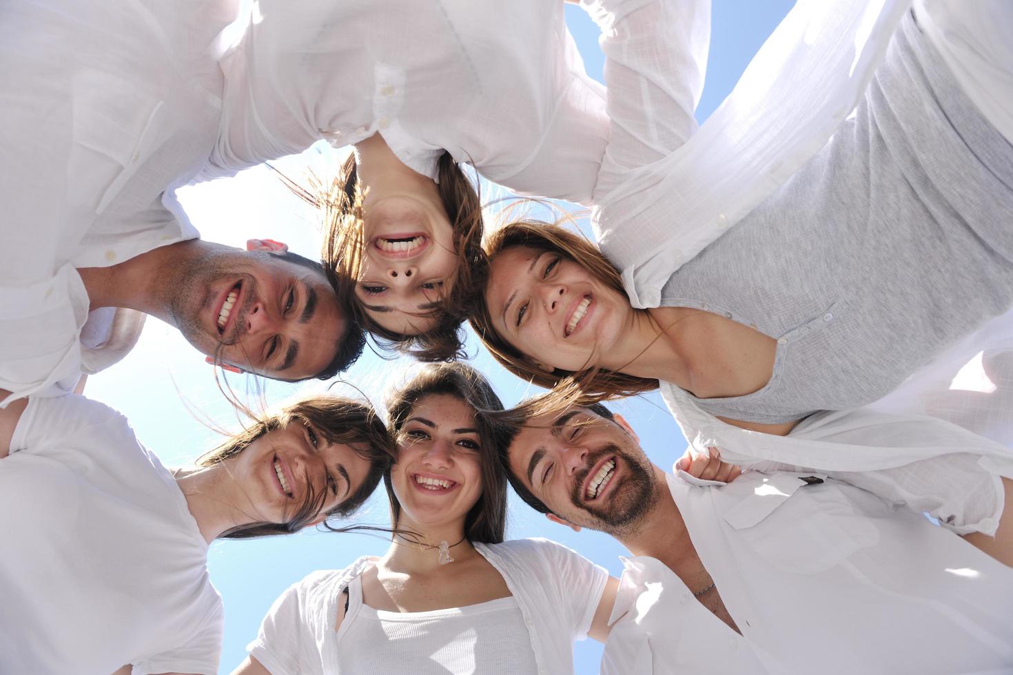 Group of happy young people in circle at beach photo