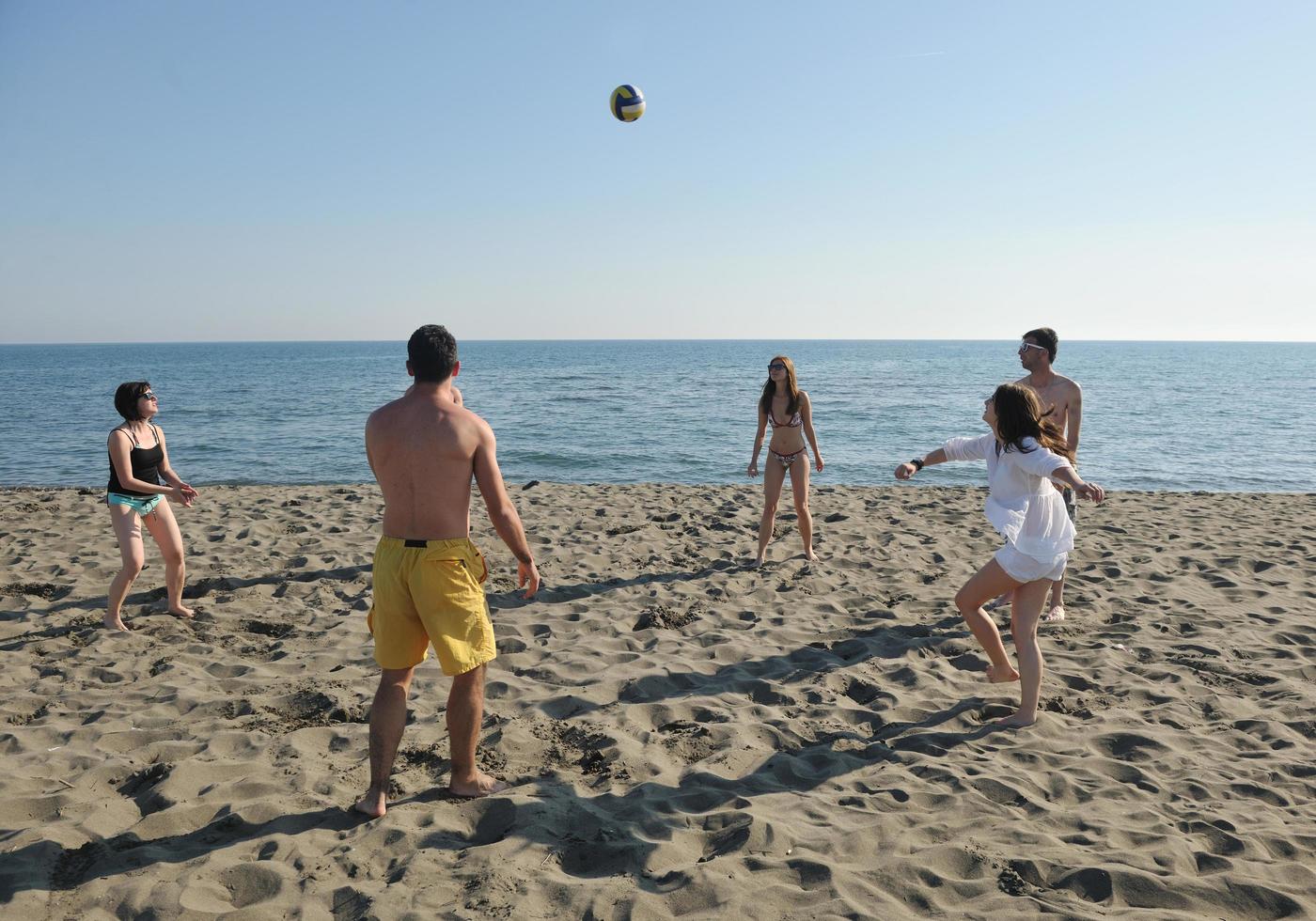 grupo de jóvenes divertirse y jugar voleibol de playa foto