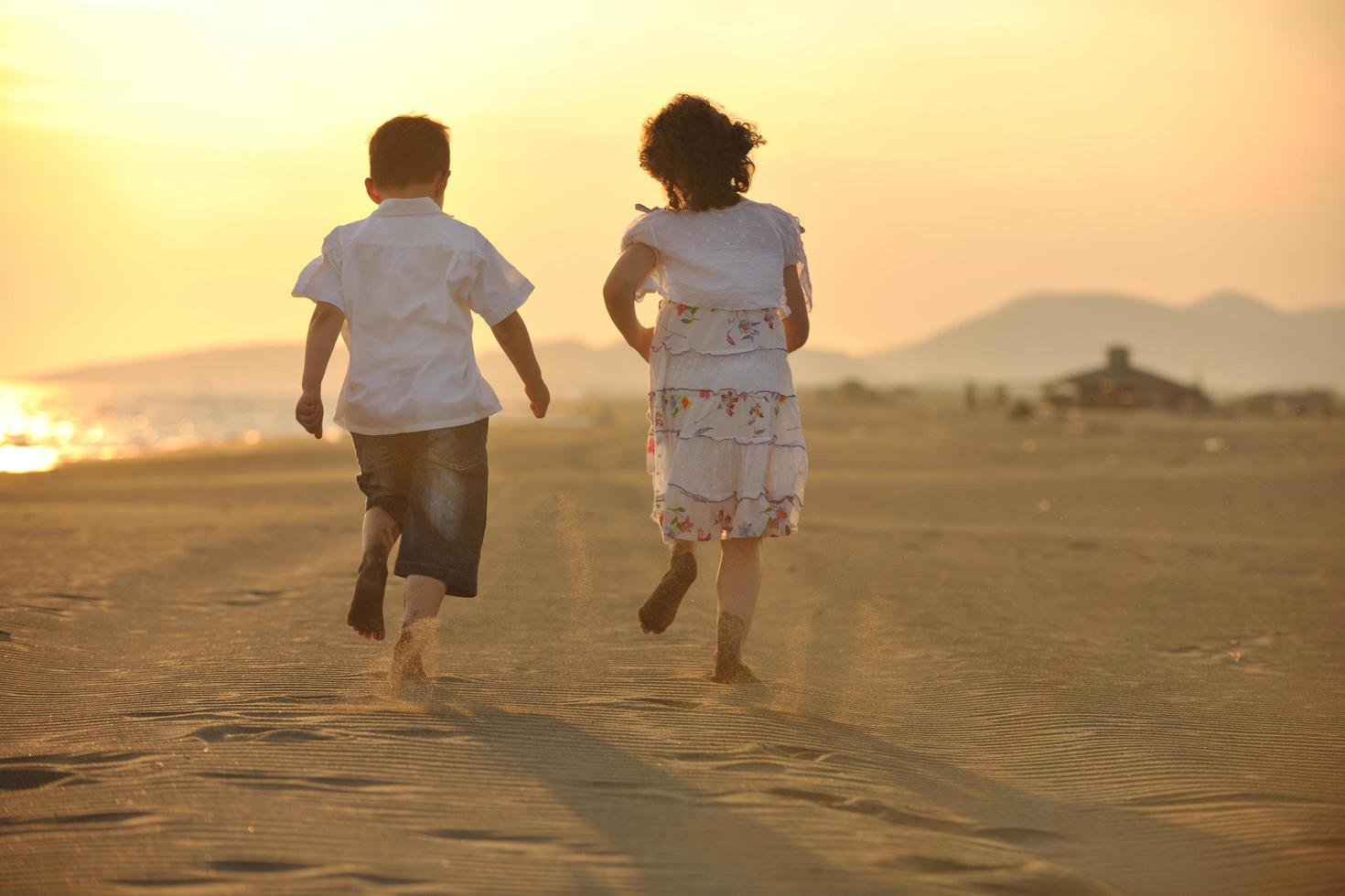 familia joven feliz divertirse en la playa al atardecer foto