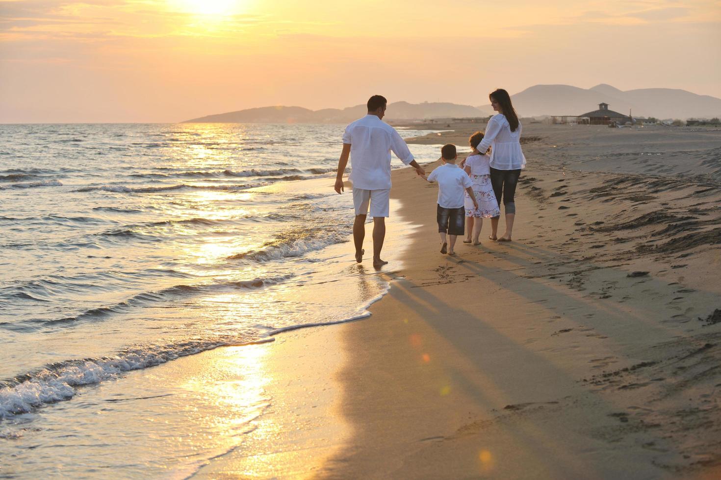 familia joven feliz divertirse en la playa al atardecer foto