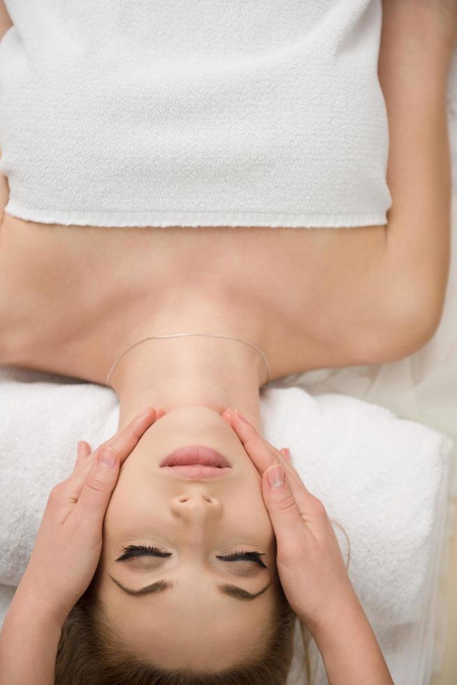 mujer recibiendo masaje facial y de cabeza en el salón de spa foto