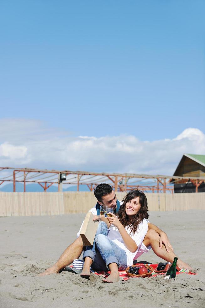 pareja joven disfrutando de un picnic en la playa foto