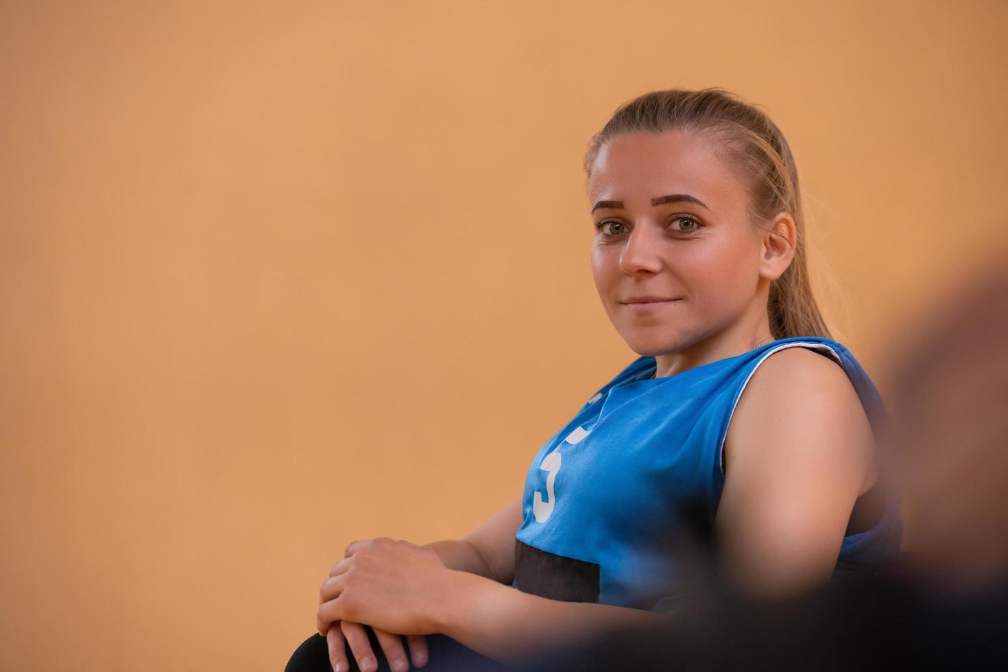 a portrait of a woman with a disability sitting in a wheelchair waiting for a basketball game to begin photo