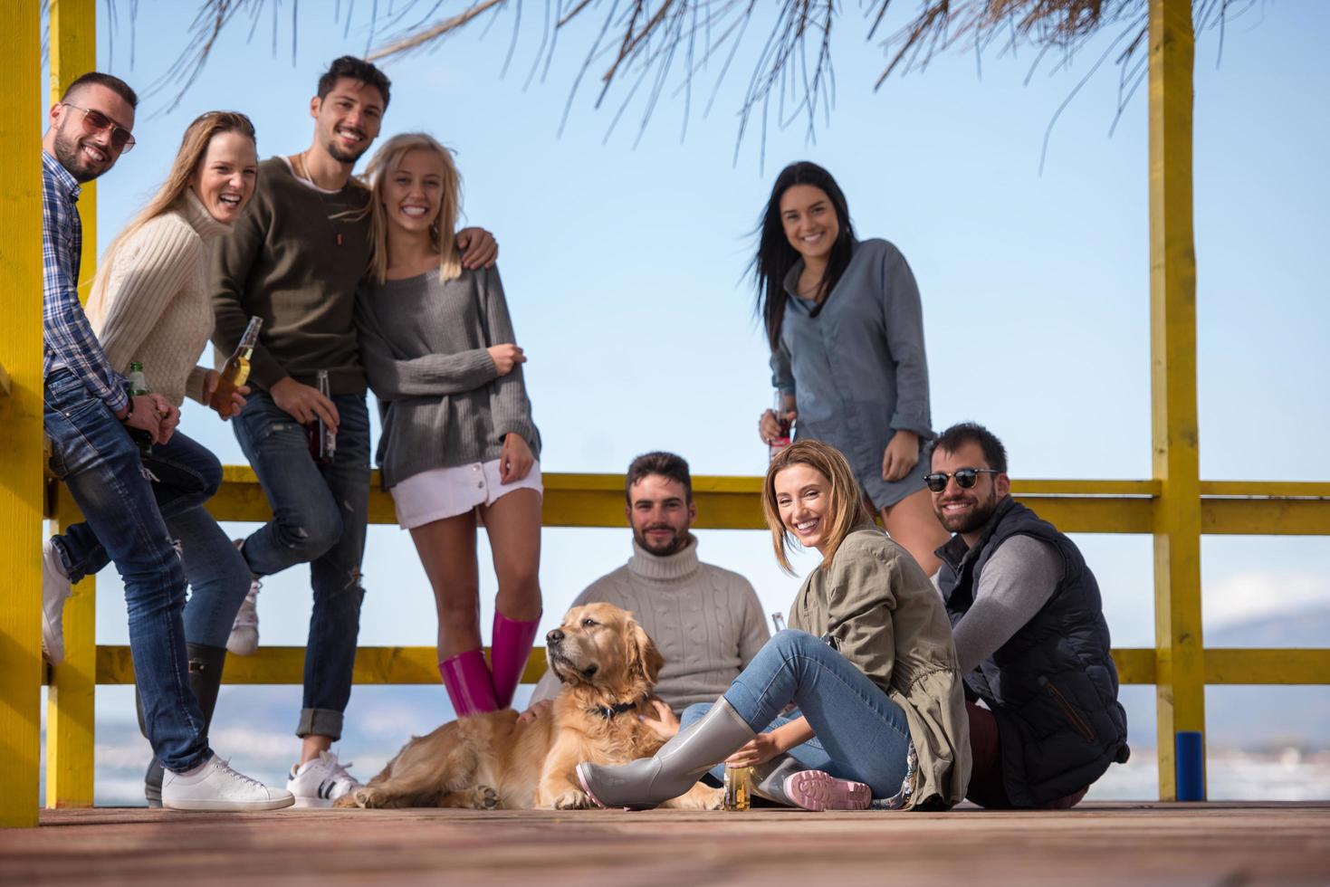 Group of friends having fun on autumn day at beach photo