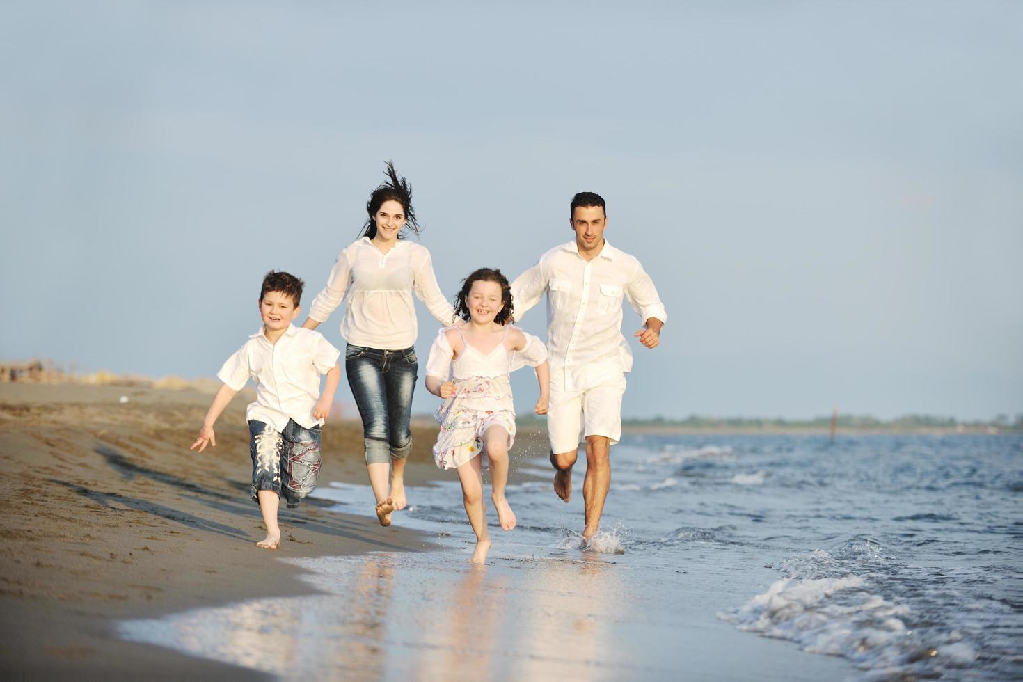 familia joven feliz divertirse en la playa al atardecer foto