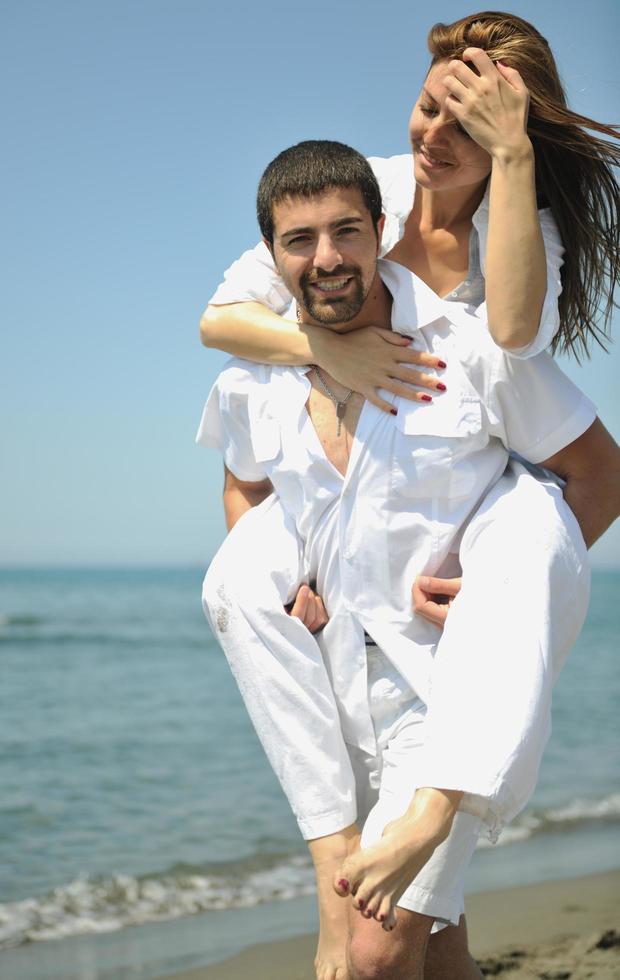 feliz pareja joven divertirse en la playa foto