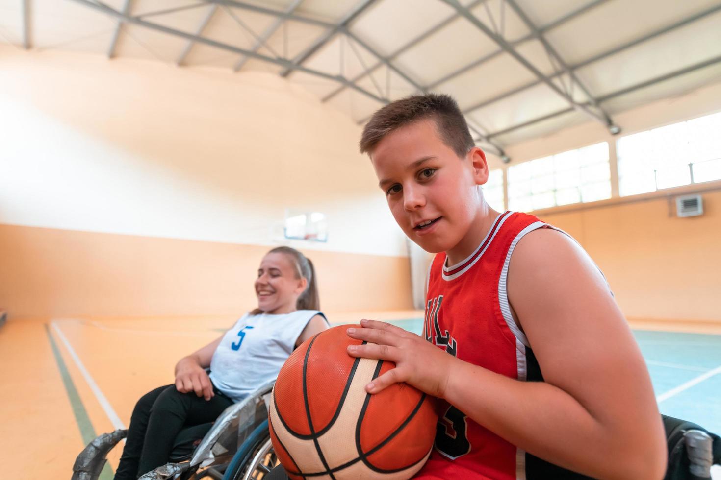 the boy sits in a wheelchair and prepares for the basketball start of the game in the big arena. Selective focus photo