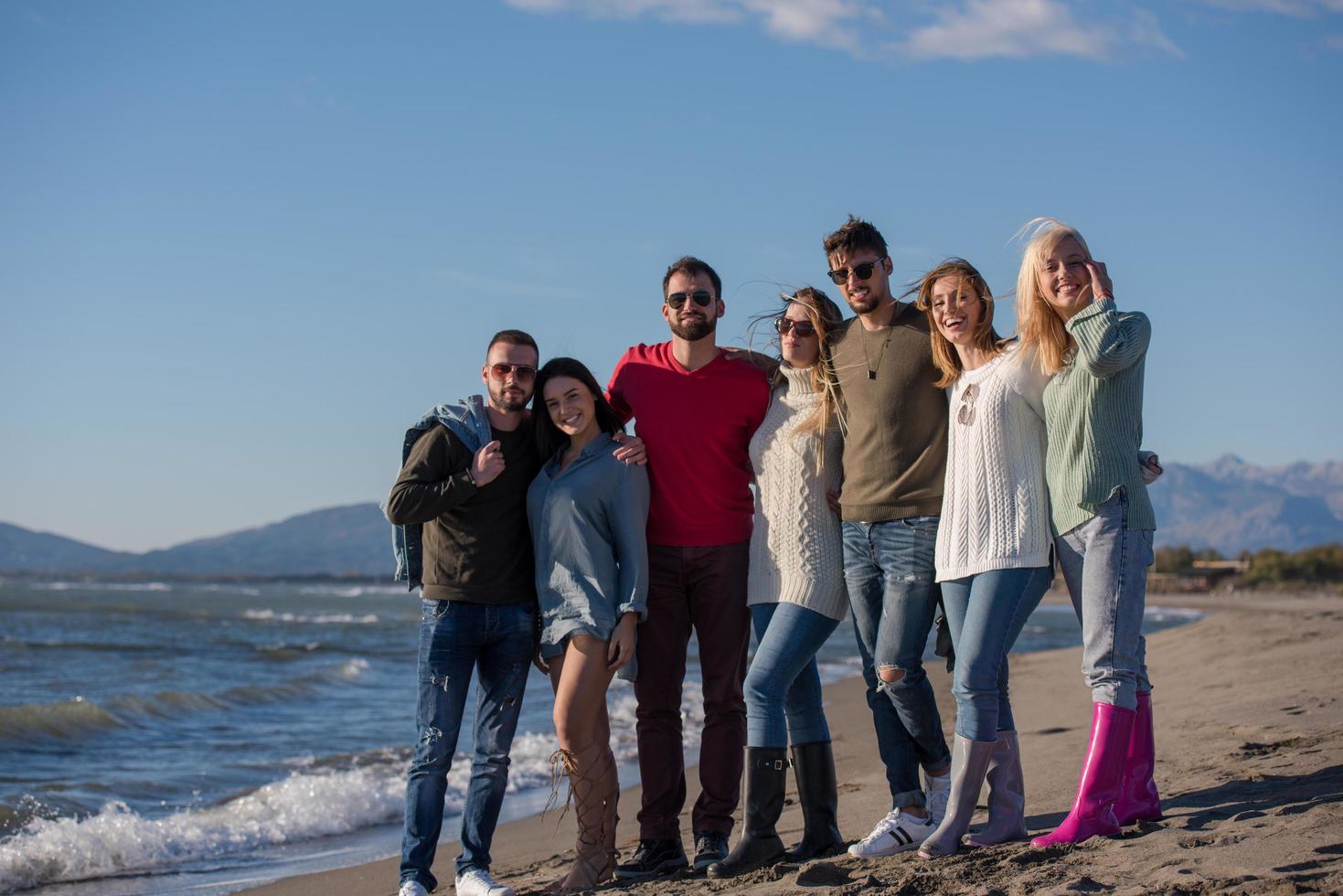 retrato de amigos divirtiéndose en la playa durante el día de otoño foto