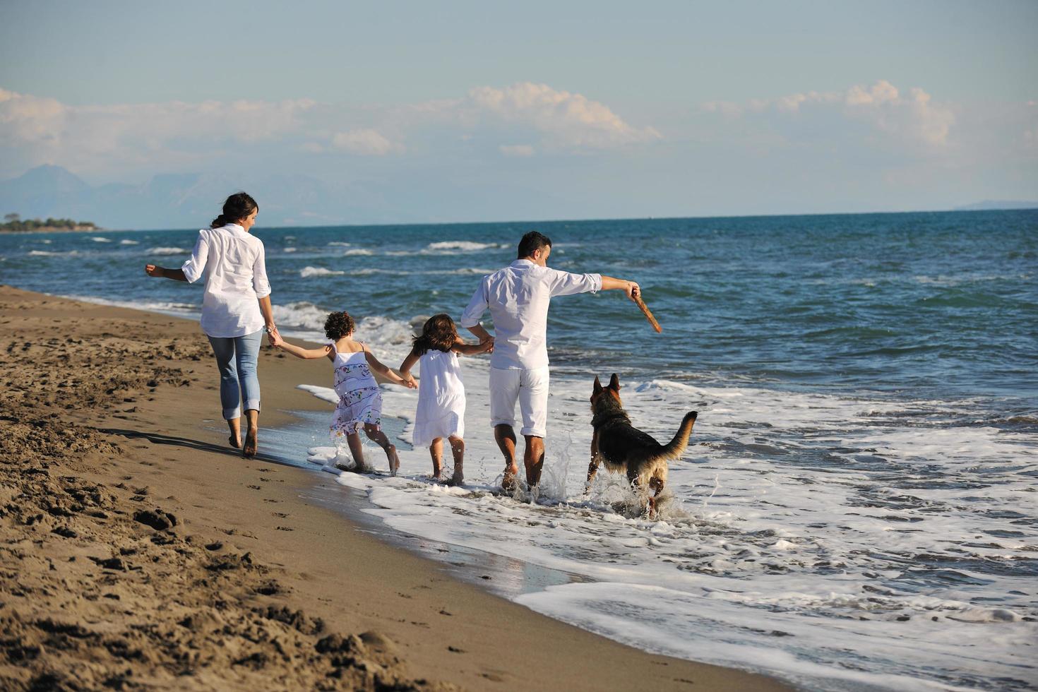 happy family playing with dog on beach photo
