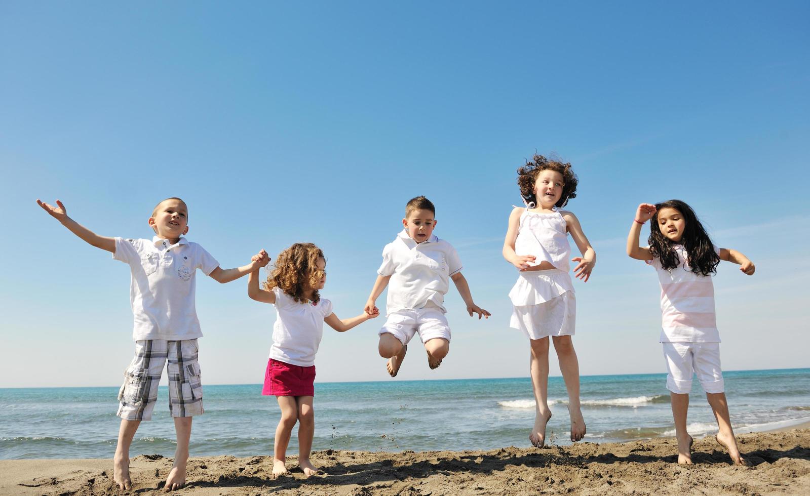 Grupo de niños felices jugando en la playa foto