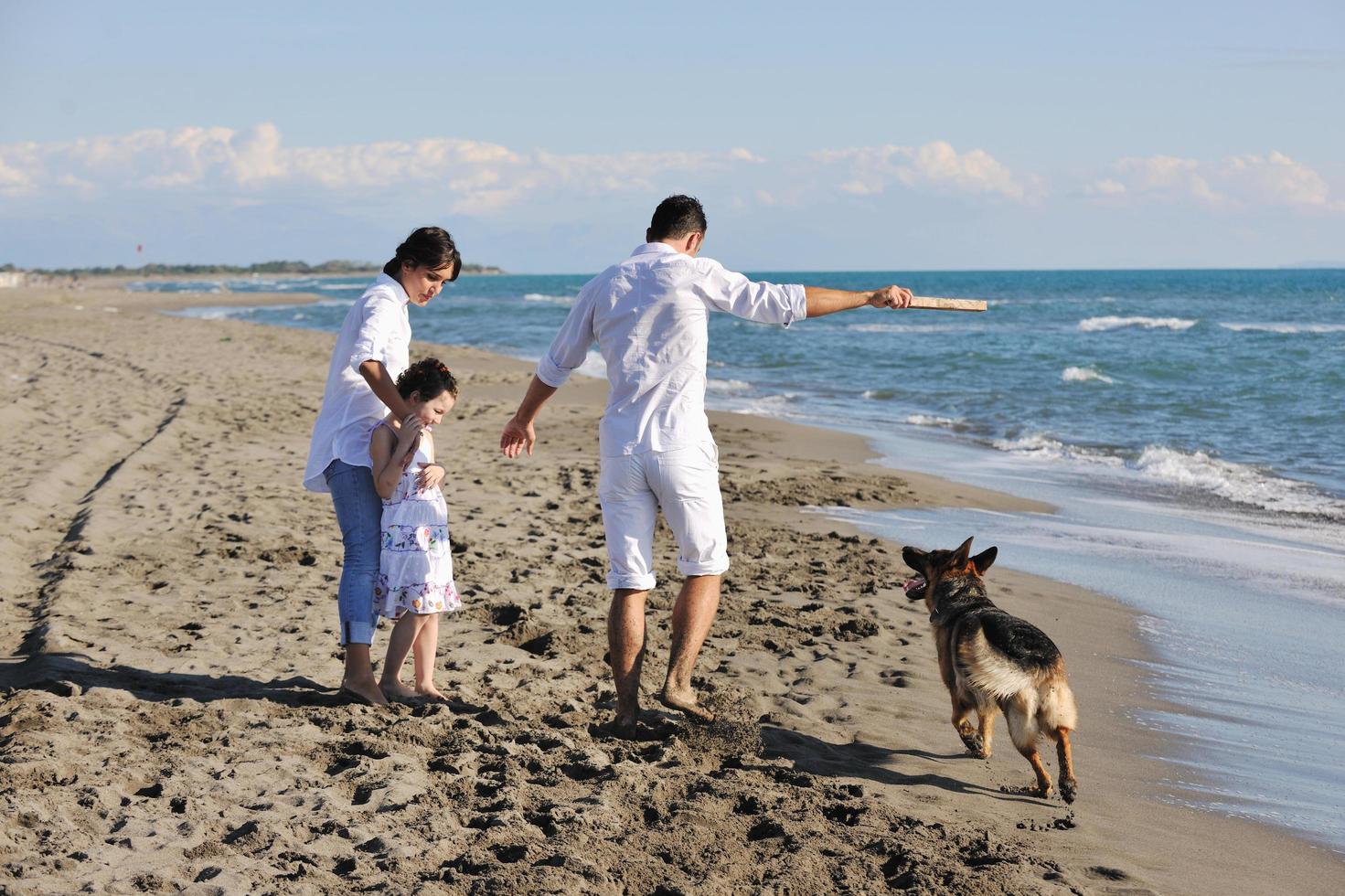 familia feliz jugando con el perro en la playa foto