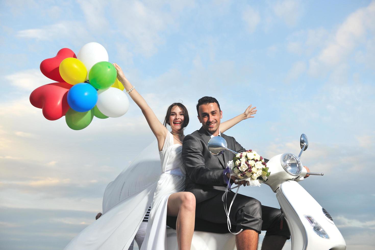 just married couple on the beach ride white scooter photo
