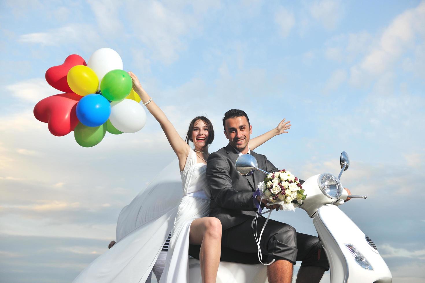 pareja de recién casados en la playa paseo scooter blanco foto