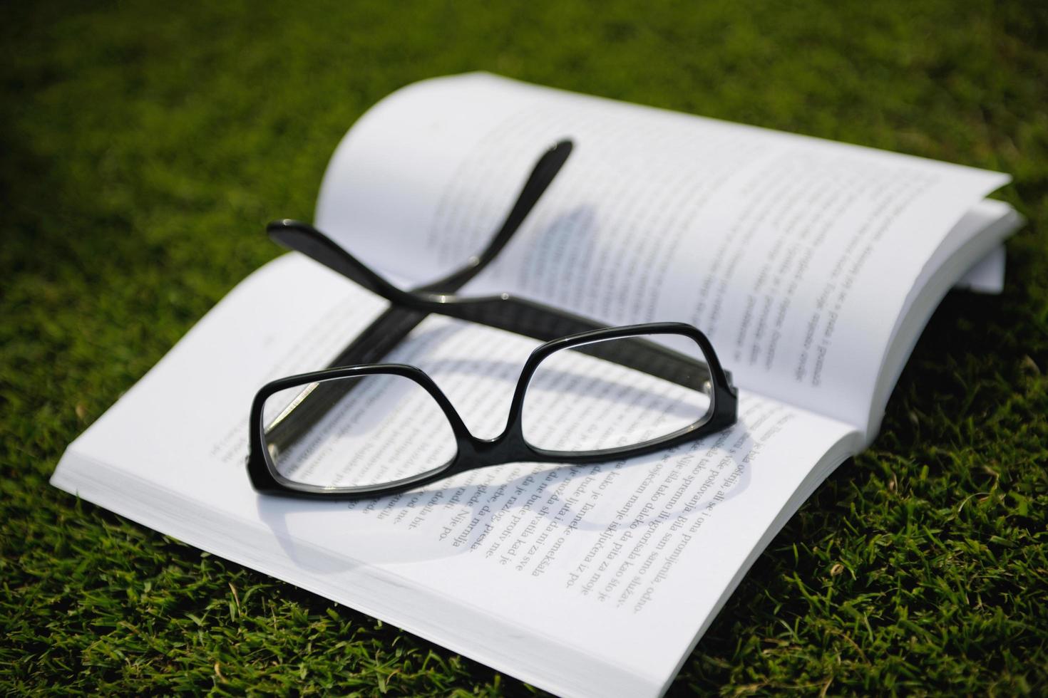 Glasses on a book outside with grass photo