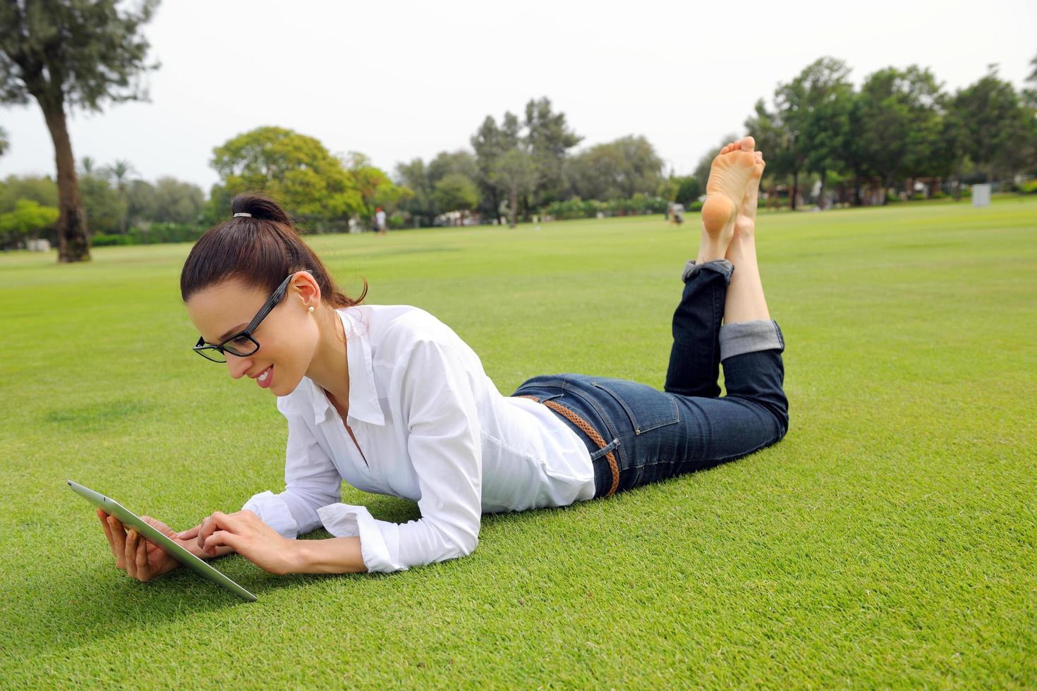 Beautiful young woman with  tablet in park photo