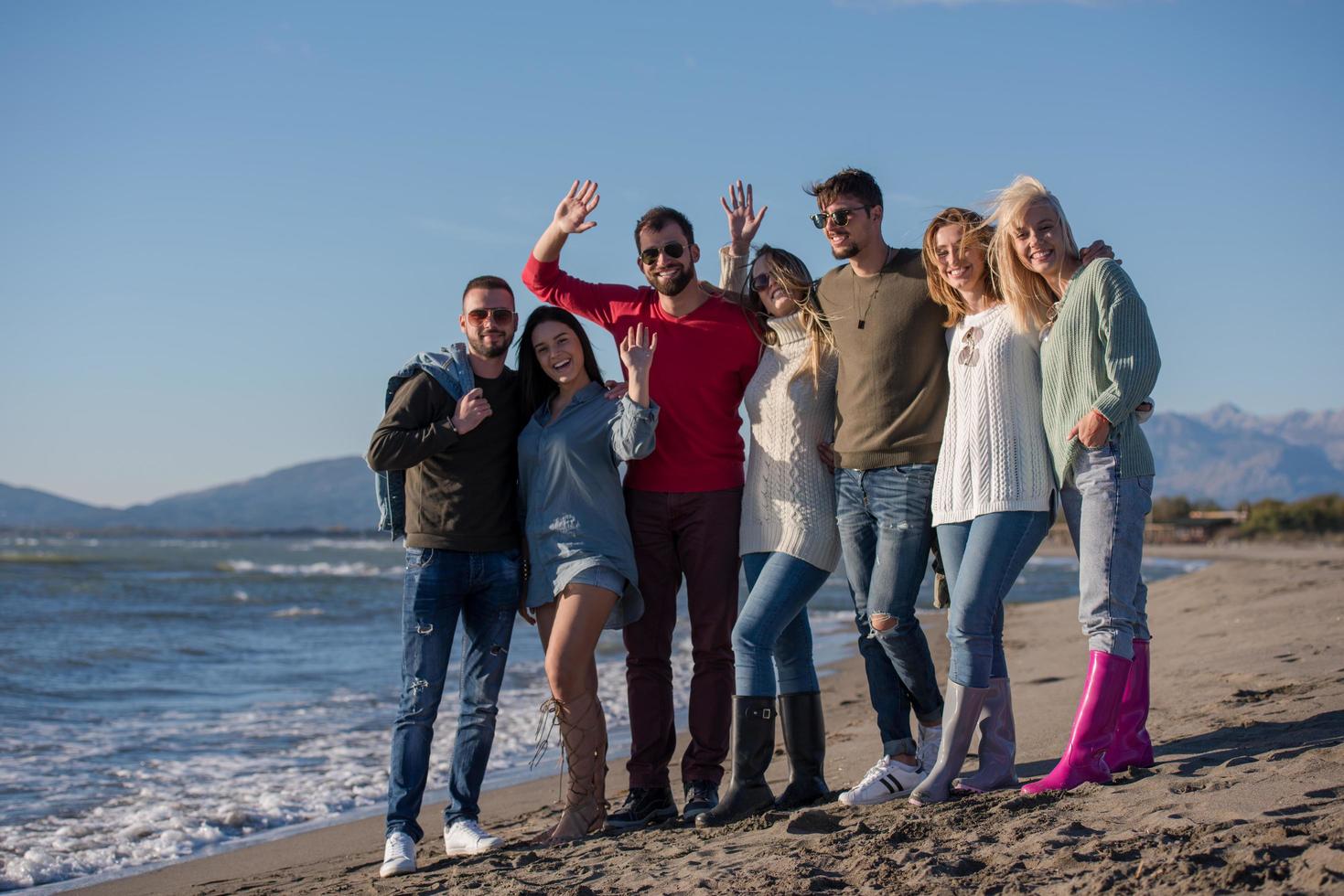 portrait of friends having fun on beach during autumn day photo