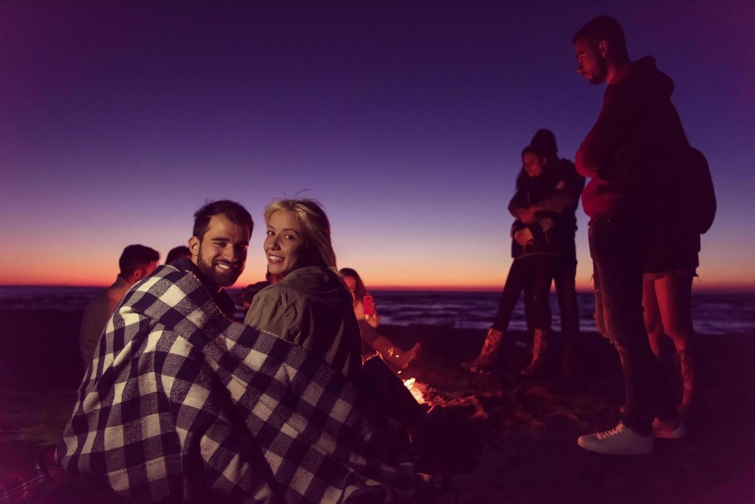 Couple enjoying with friends at sunset on the beach photo