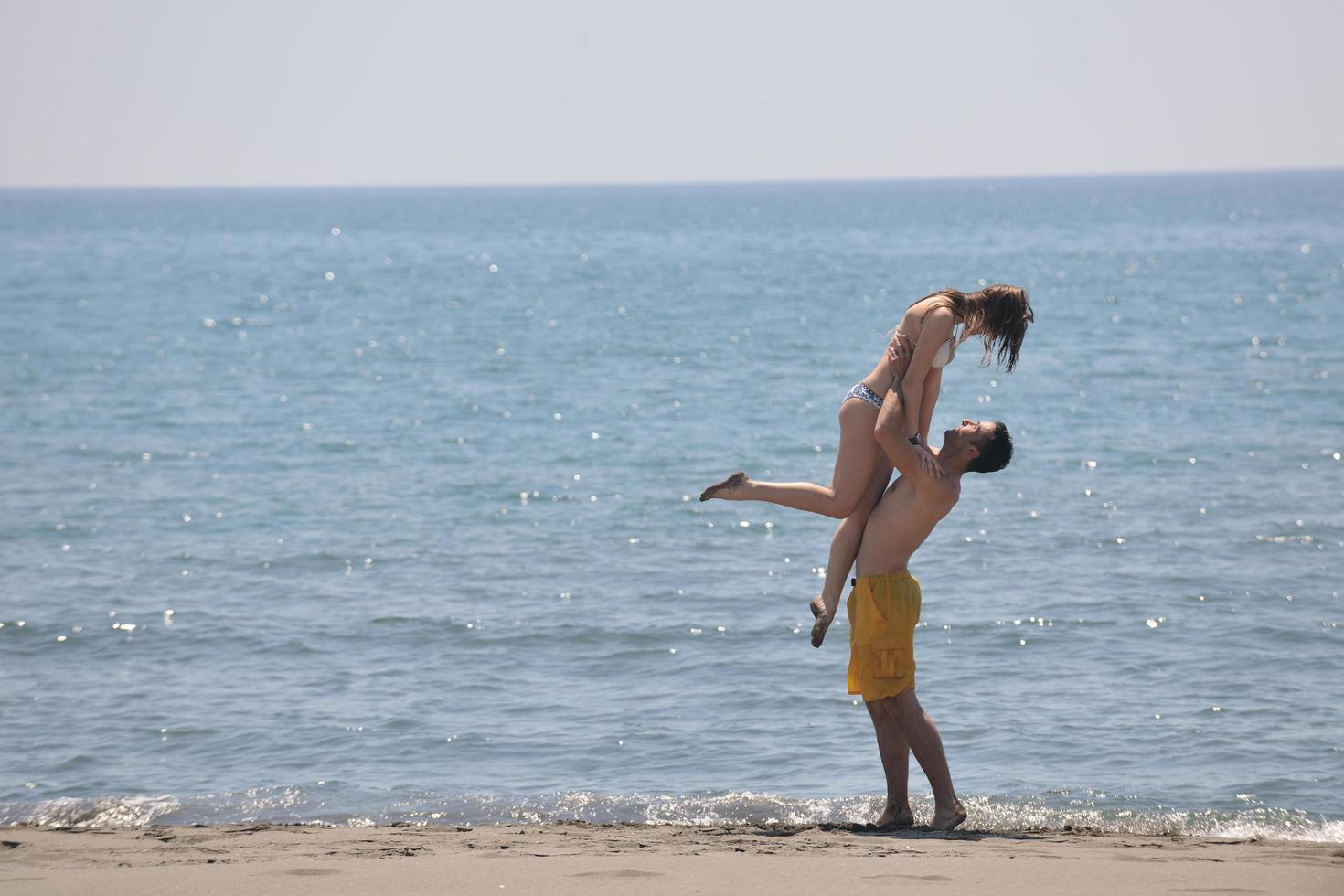 feliz pareja joven divertirse en la playa foto