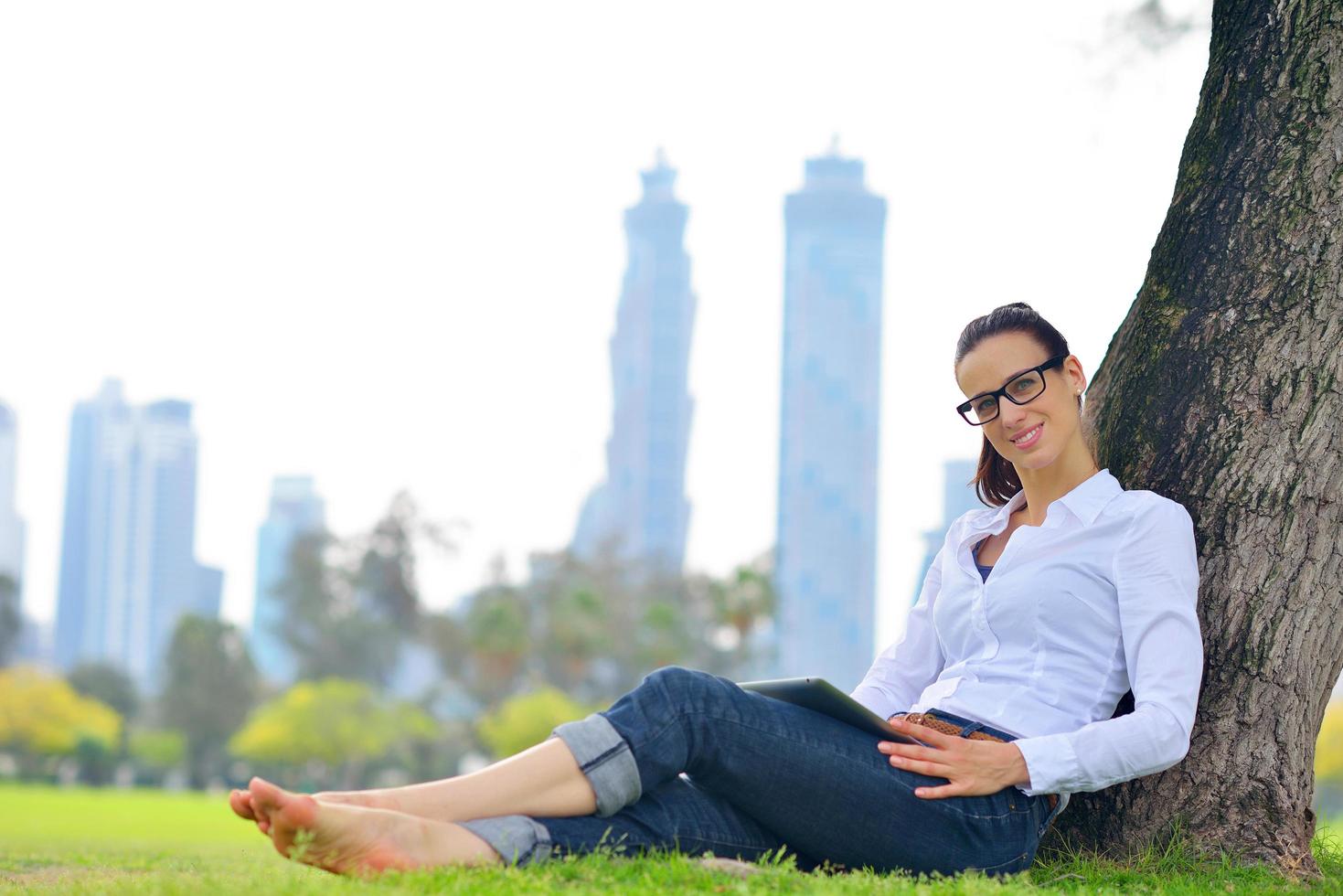 Beautiful young woman with  tablet in park photo